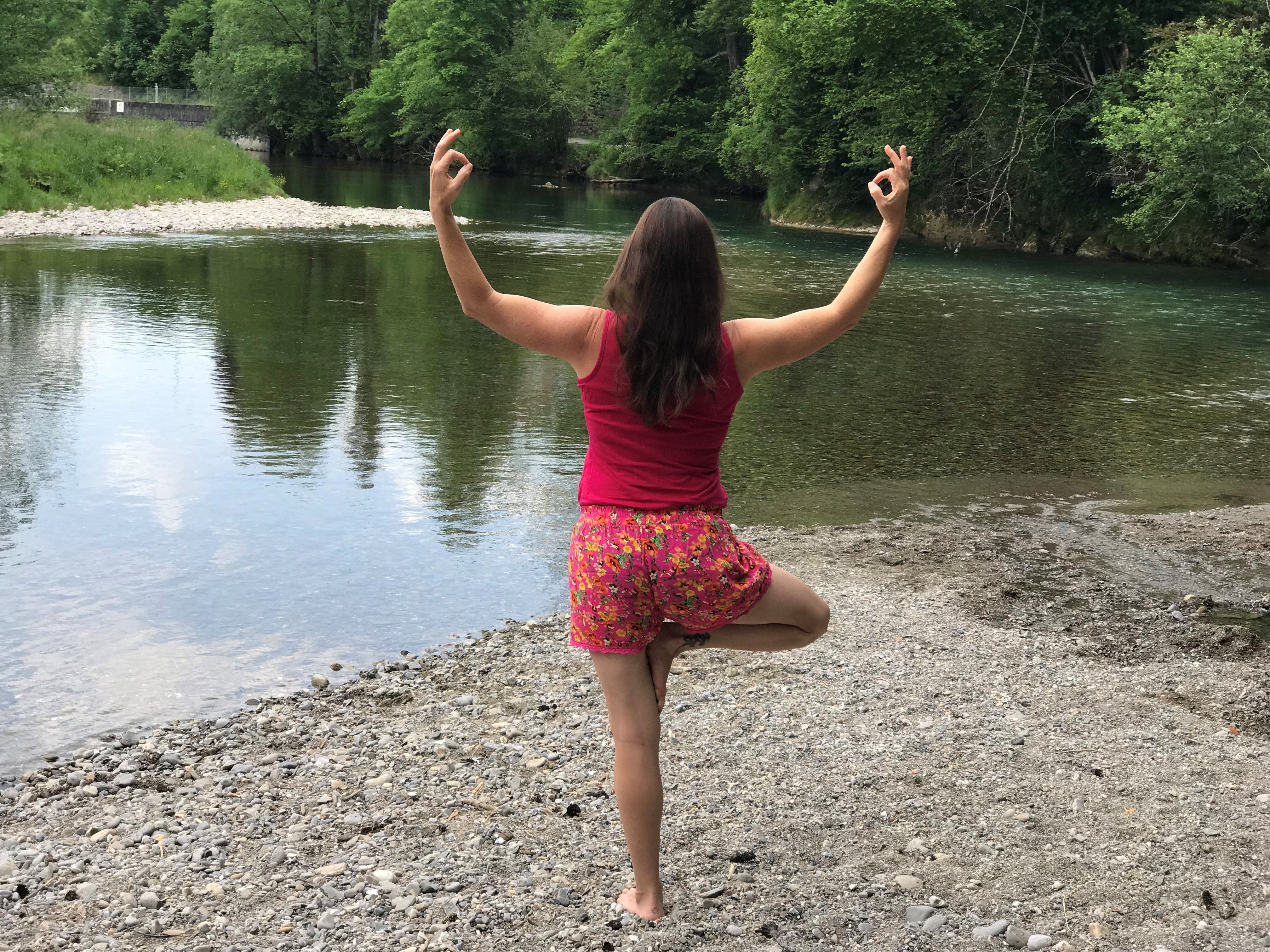 Yoga im Freien: meditative Pose am Wasser, umgeben von Natur, ideal für Entspannung und Wellness.