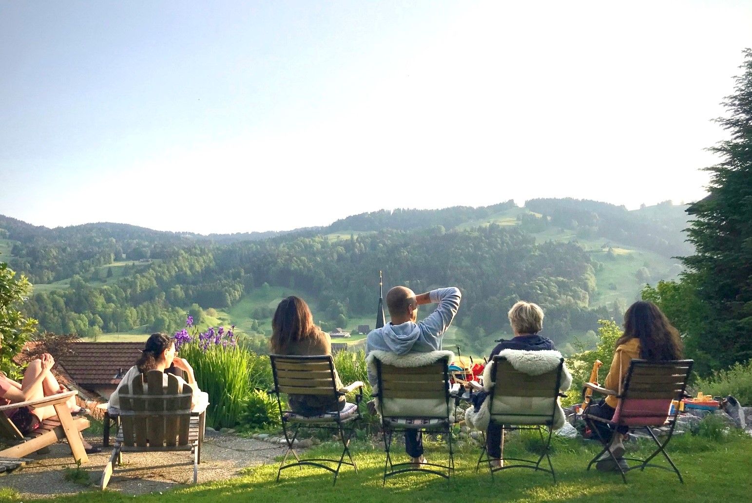 Yoga Retreat: Gruppe entspannt in der Natur mit Blick auf die Berge und eine grüne Landschaft.