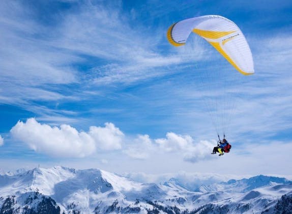 Lot paralotnią nad Engelberg-Brunni z pokrytymi śniegiem górami i niebieskim niebem.