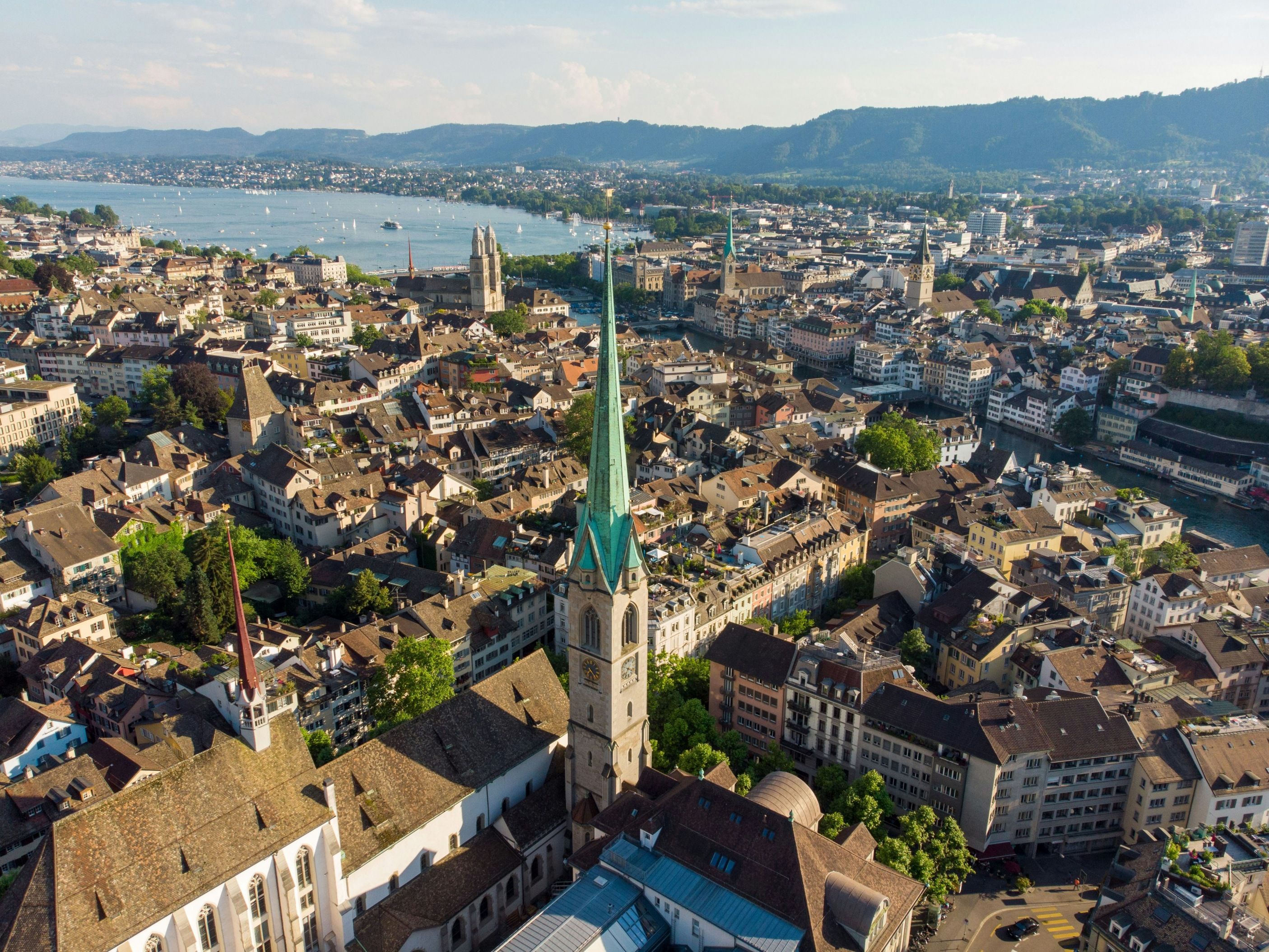 Zurich : Vue de la vieille ville avec un bâtiment historique et le paysage suisse en arrière-plan.
