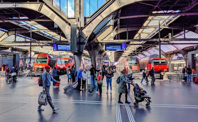 Gare de Zurich : Station animée avec des voyageurs et des trains, idéale pour tes explorations en Suisse.