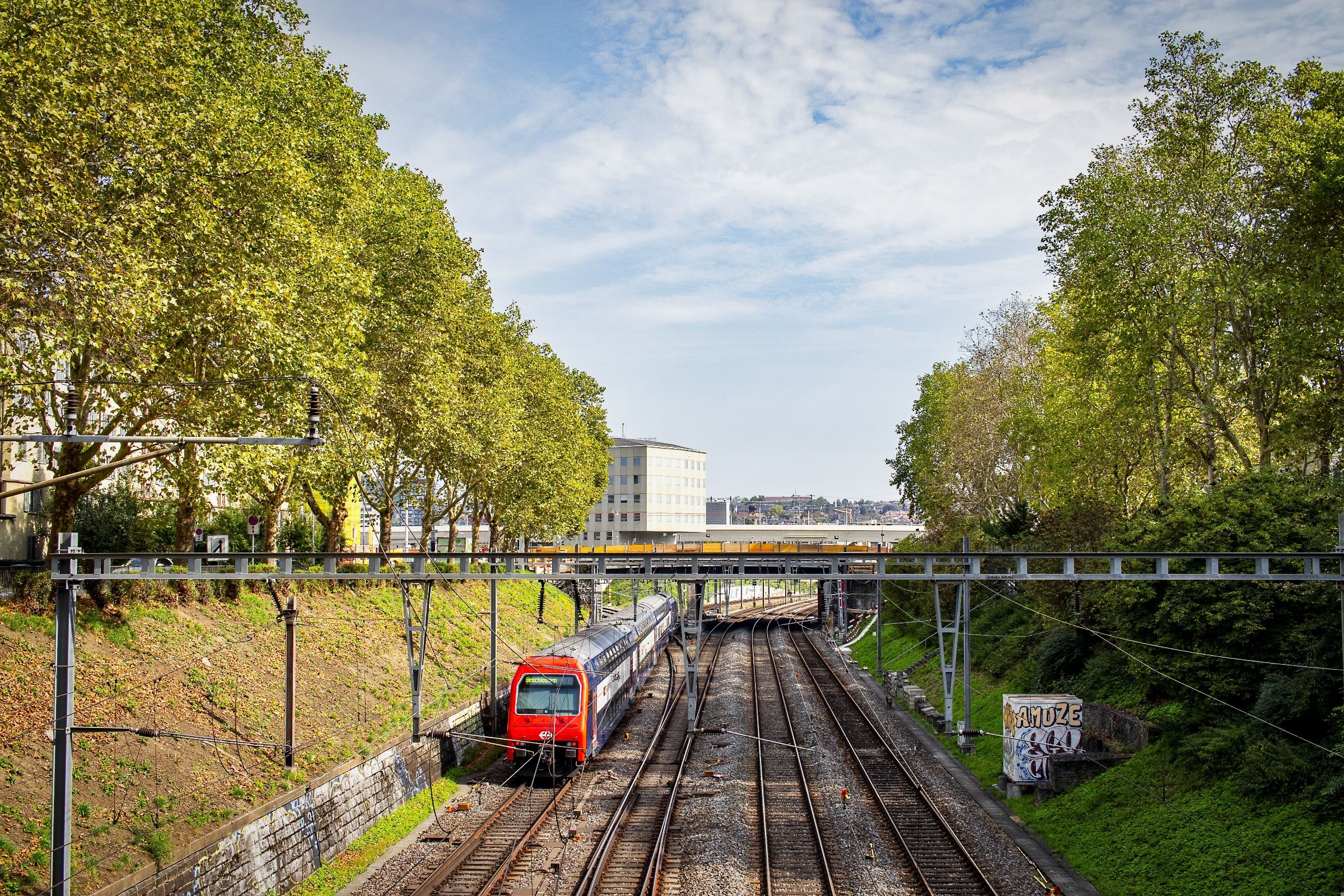Zürich: stasiun kereta modern dikelilingi kereta dan pemandangan indah dikelilingi pohon. Sempurna untuk petualangan dan penemuan.