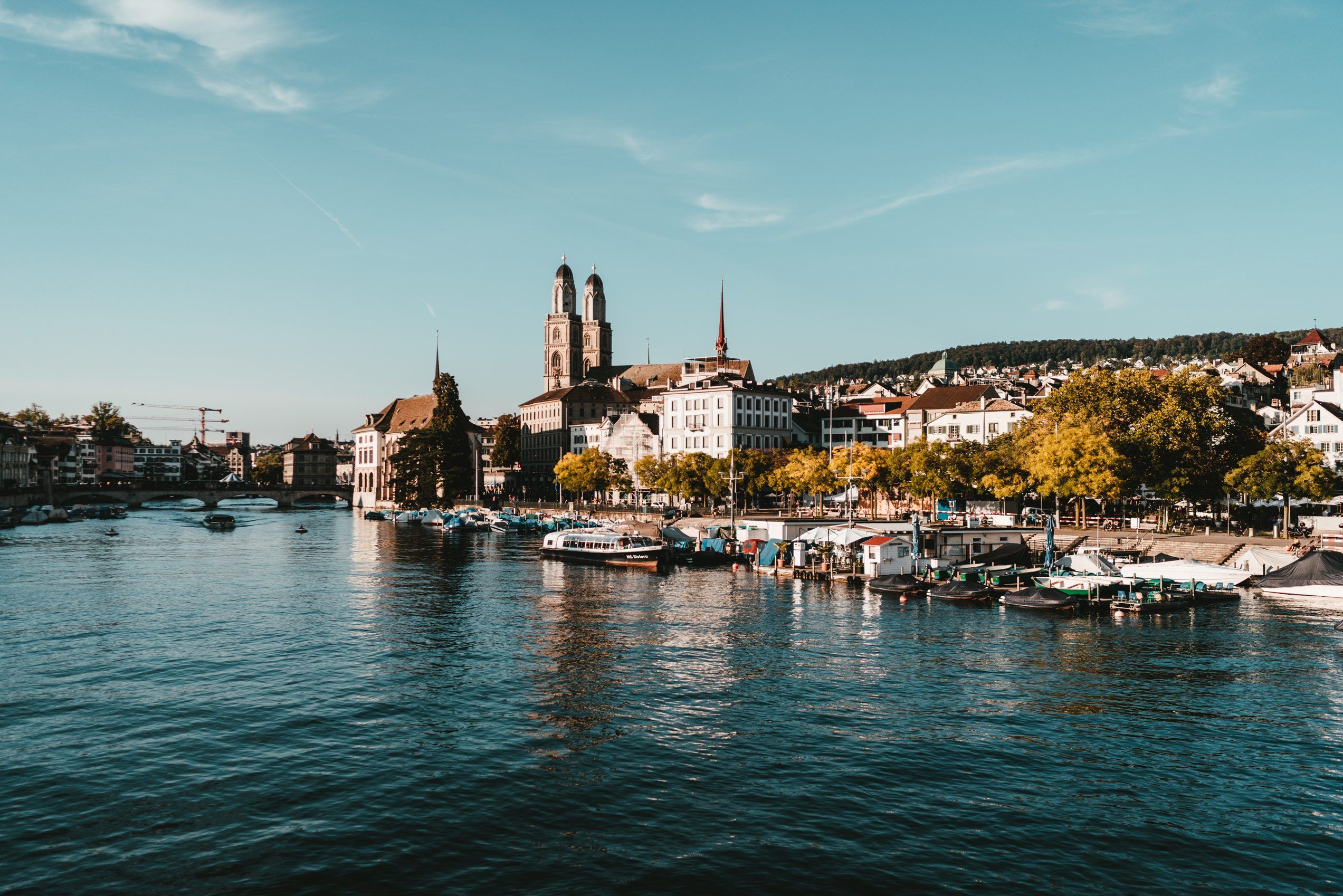 Zurich: pemandangan bandar yang indah dengan air, seni bina, bot dan pokok-pokok.