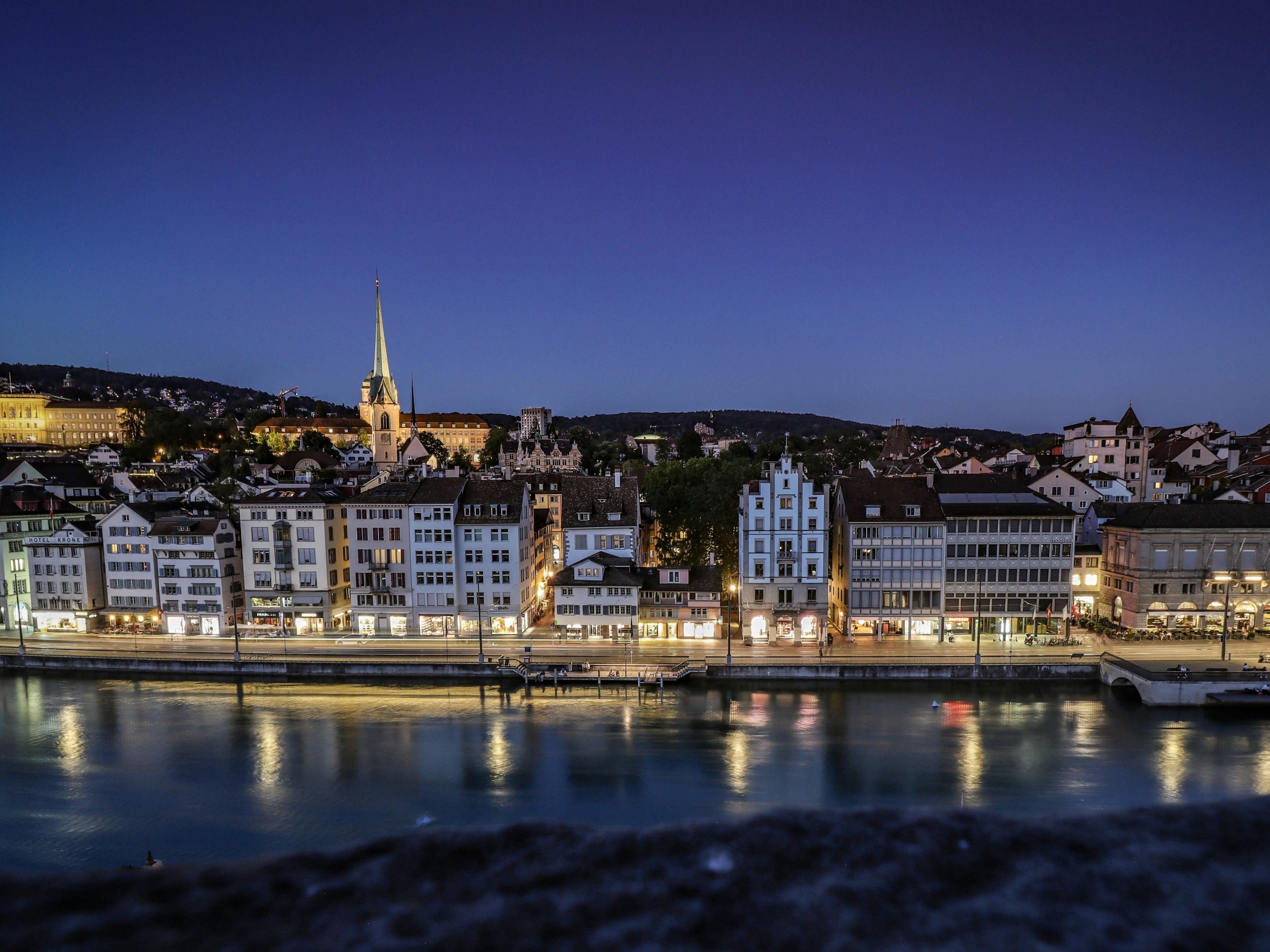 Zurich : vue sur la vieille ville illuminée au bord de la Limmat avec des bâtiments historiques.