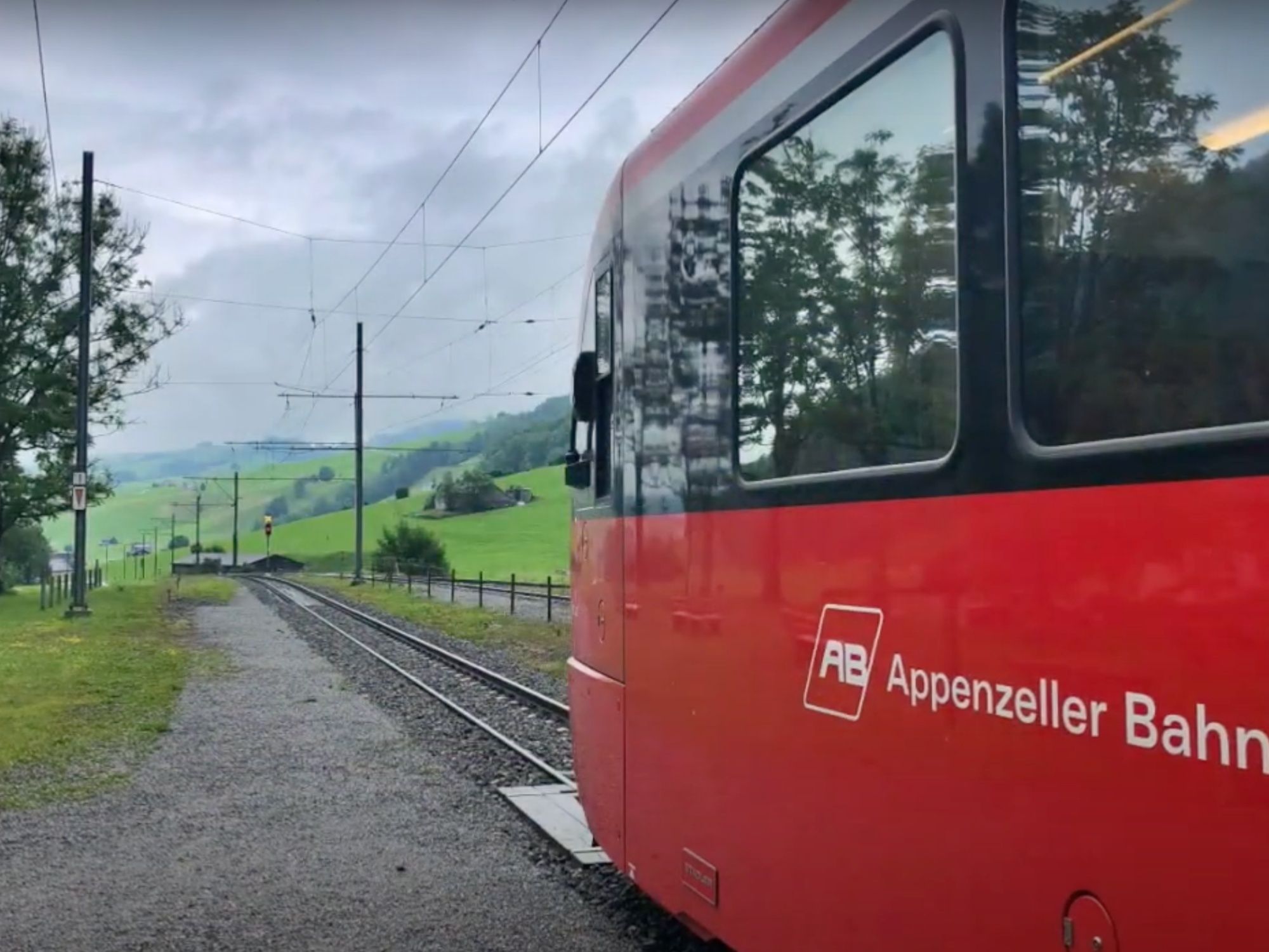 ツーク・ヴァッサーアウエン：緑の丘と自然の中の鉄道線路の絶景