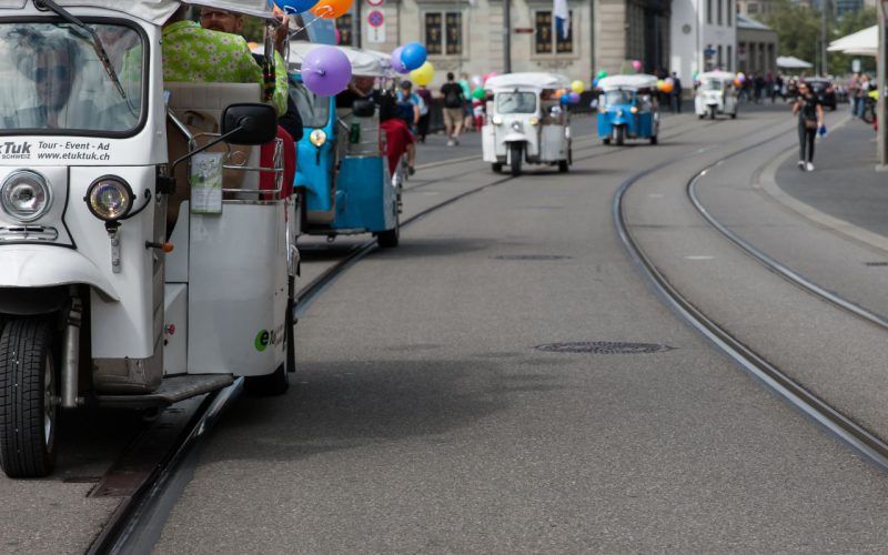 Tuk-Tuk-tur i Zürich på Bahnhofstrasse med deltagere og farverige balloner.