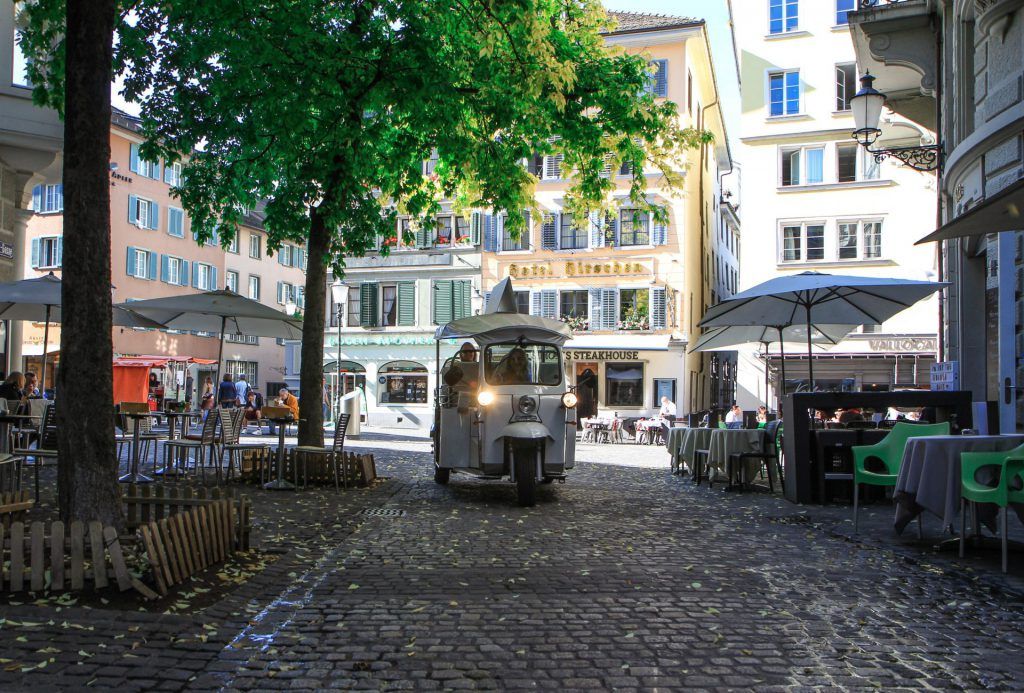 ตุ๊กตุ๊กขับผ่านเมืองเก่าที่ซูริก ผู้โดยสารนั่งด้านนอก