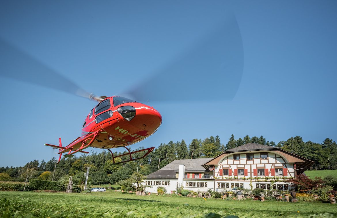 Επαναληπτική πτήση με ελικόπτερο πάνω από το Beromünster με κόκκινο ελικόπτερο στον μπλε ουρανό.