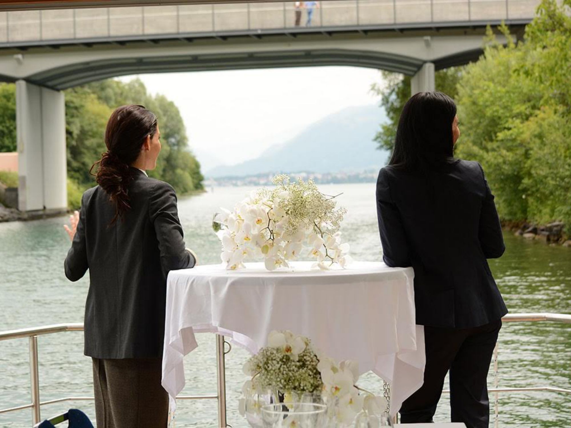 Eventfloss: Kobiety podziwiają widok na krajobraz wodny z kwiatami na pierwszym planie.