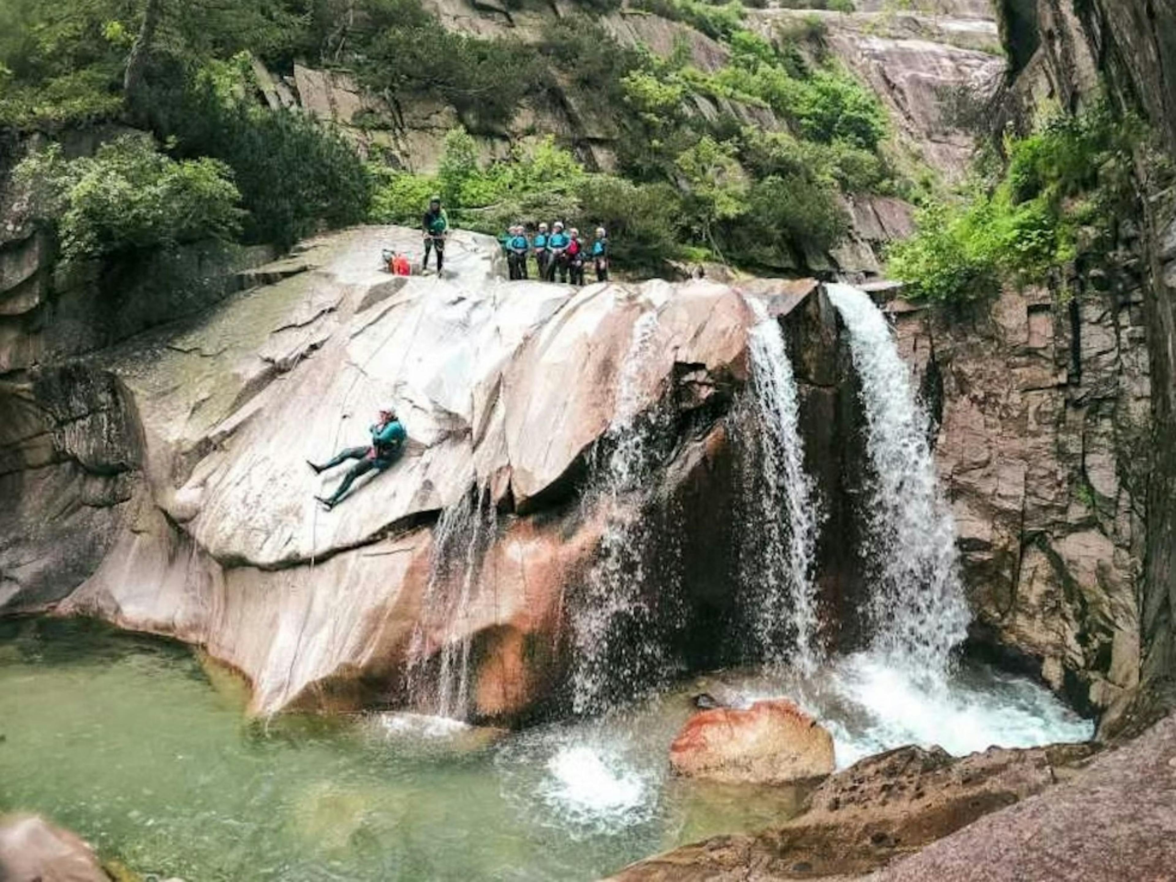 Canyoning: Rutschen in beeindruckenden Felslandschaften am Grimselpass mit Team, Natur und Wasserfall.