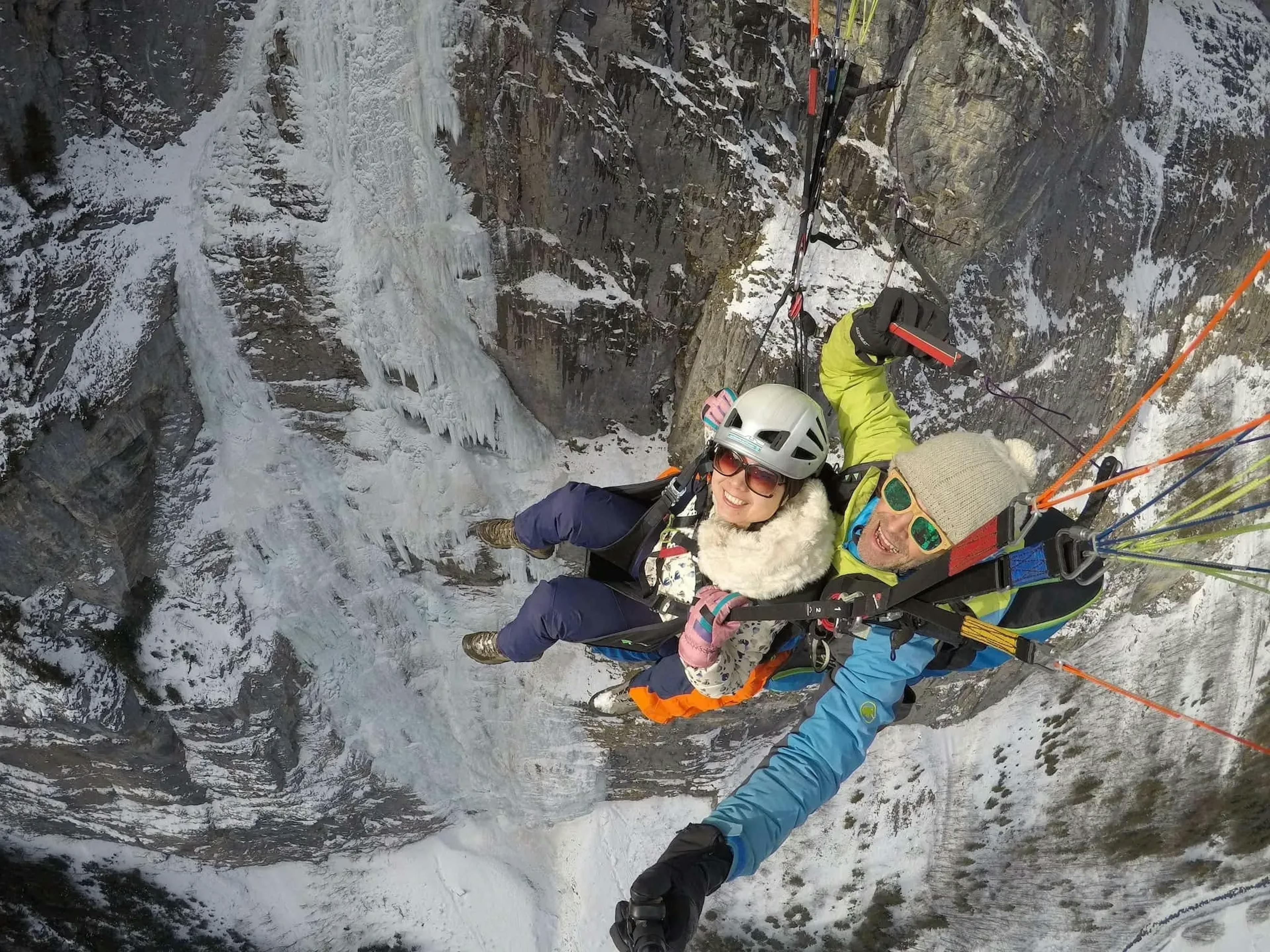 Paragliding over a snow-covered landscape with two people