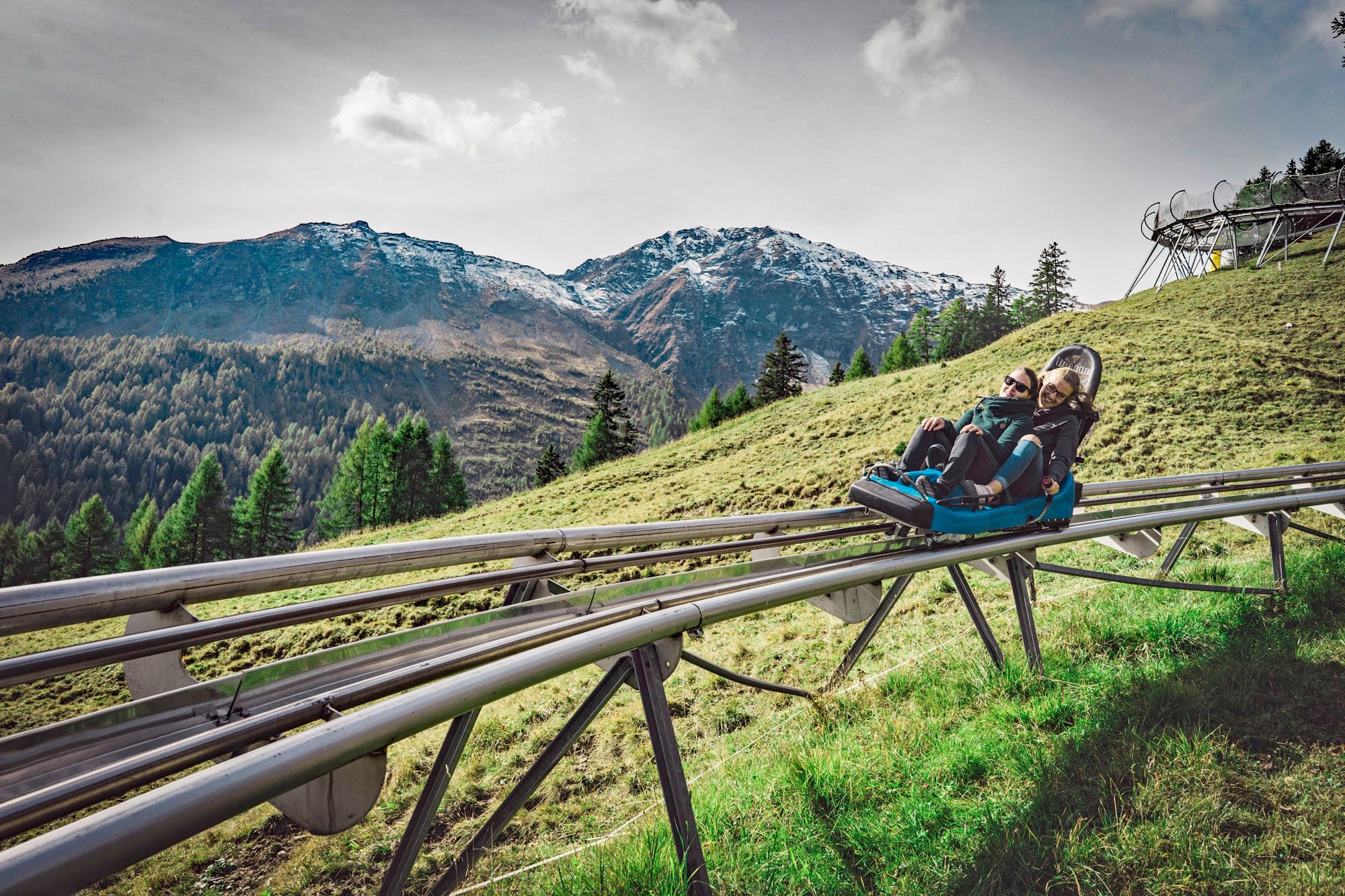 Kereta Luncur Pradaschier di musim panas, bersenang-senang menuruni bukit sambil menikmati pemandangan pegunungan.