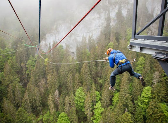 Canyon Swing: aufregendes Abenteuer über der Pissot Schlucht, umgeben von dichten Wäldern.