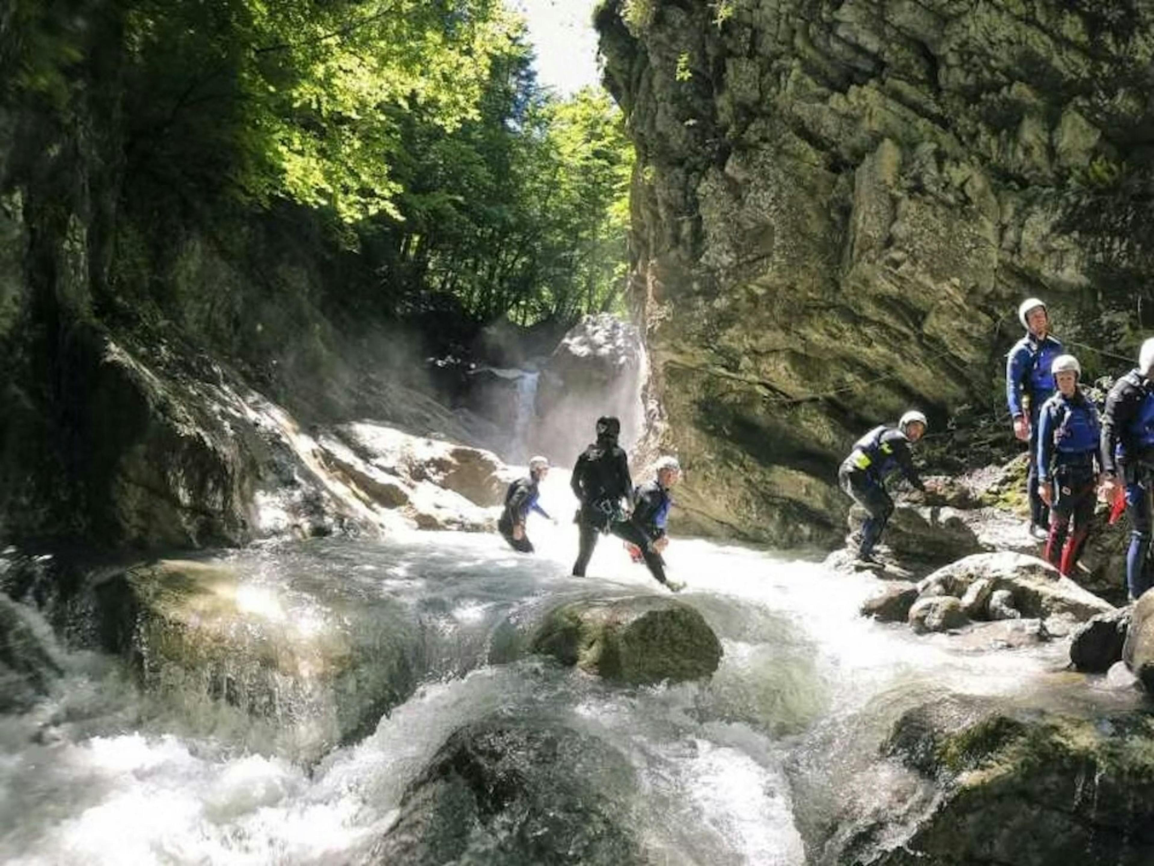 Canyoning v kaňonovej oblasti Saxet: Skupina skúma divočinu s vodopádmi a skalami.