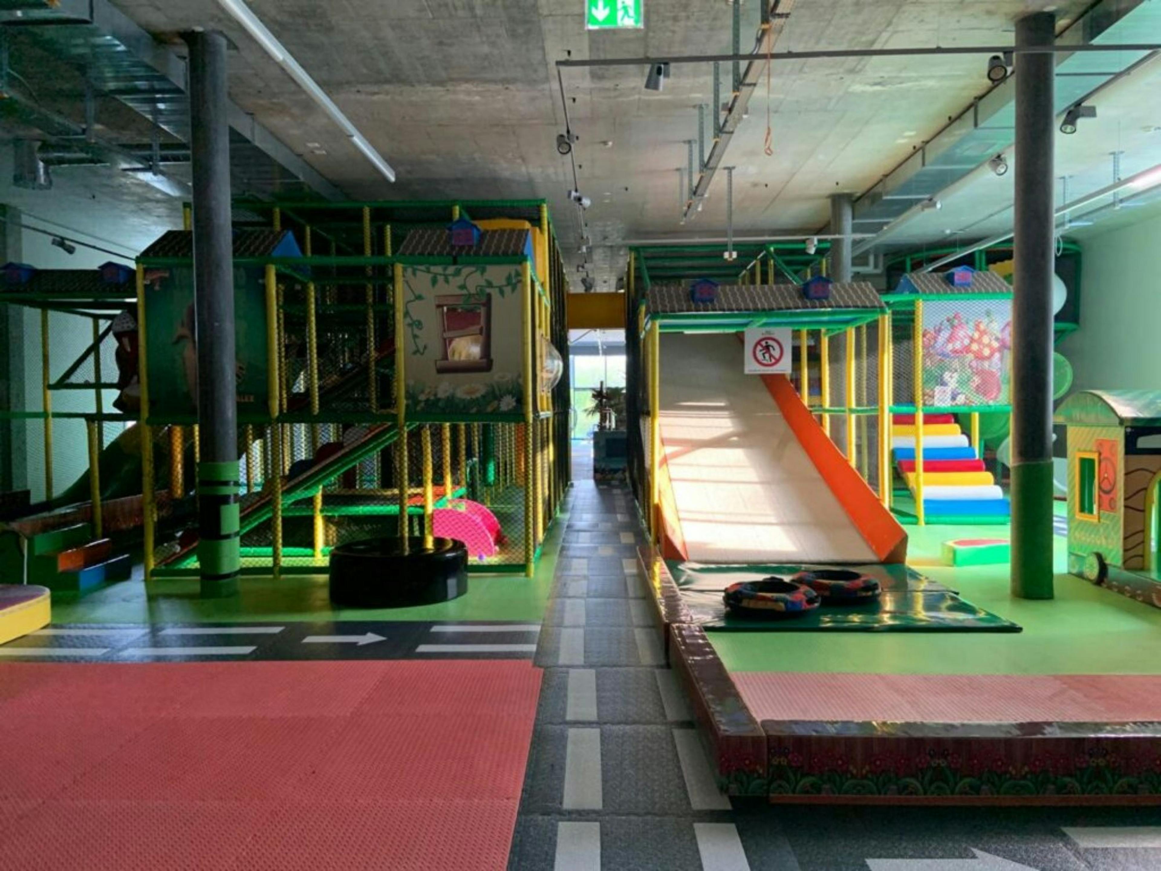 Kids Fun Park Etoy: paisaje de juegos con toboganes, redes de escalada y coloridas áreas de juego para niños.