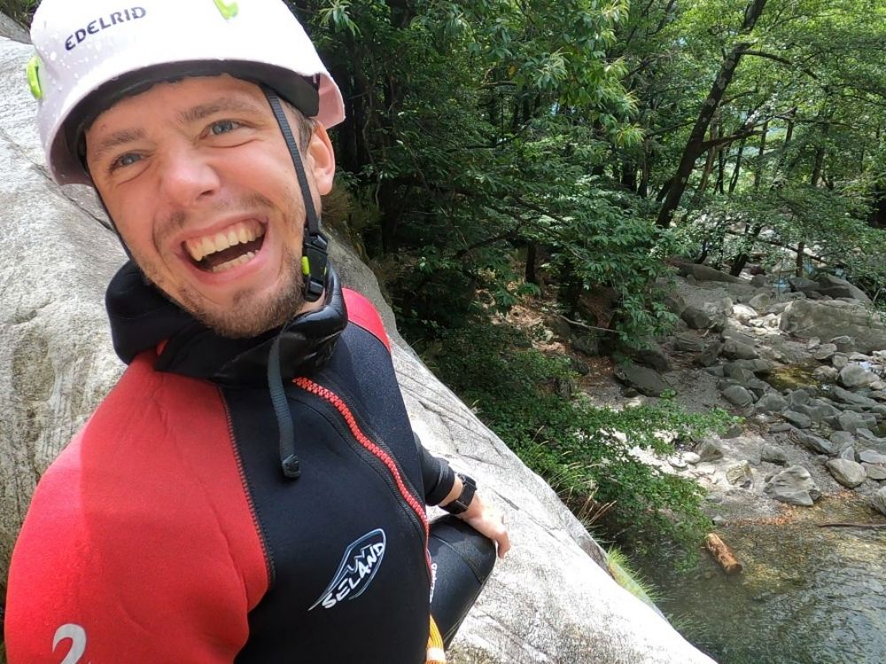 Kolejki górskie na kanionach: Mężczyzna w kombinezonie neoprenowym podczas przygody na świeżym powietrzu, otoczony zieloną naturą.