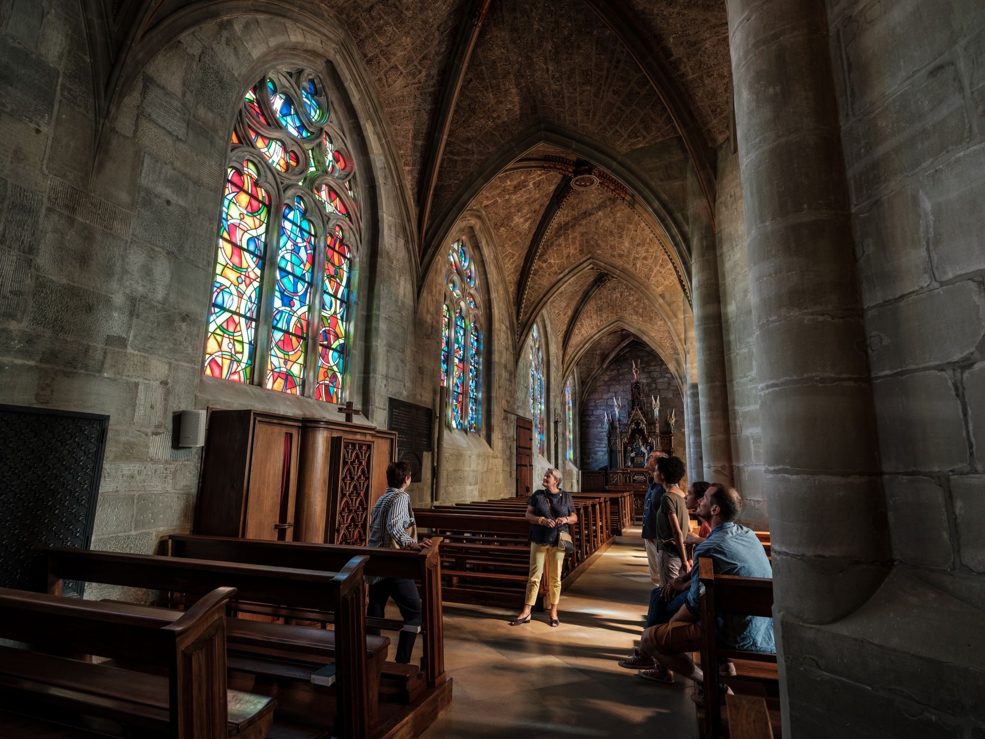 Gereja: Pandangan bahagian dalam dengan tingkap berwarna-warni dan pengunjung, suasana romantis di Romont.