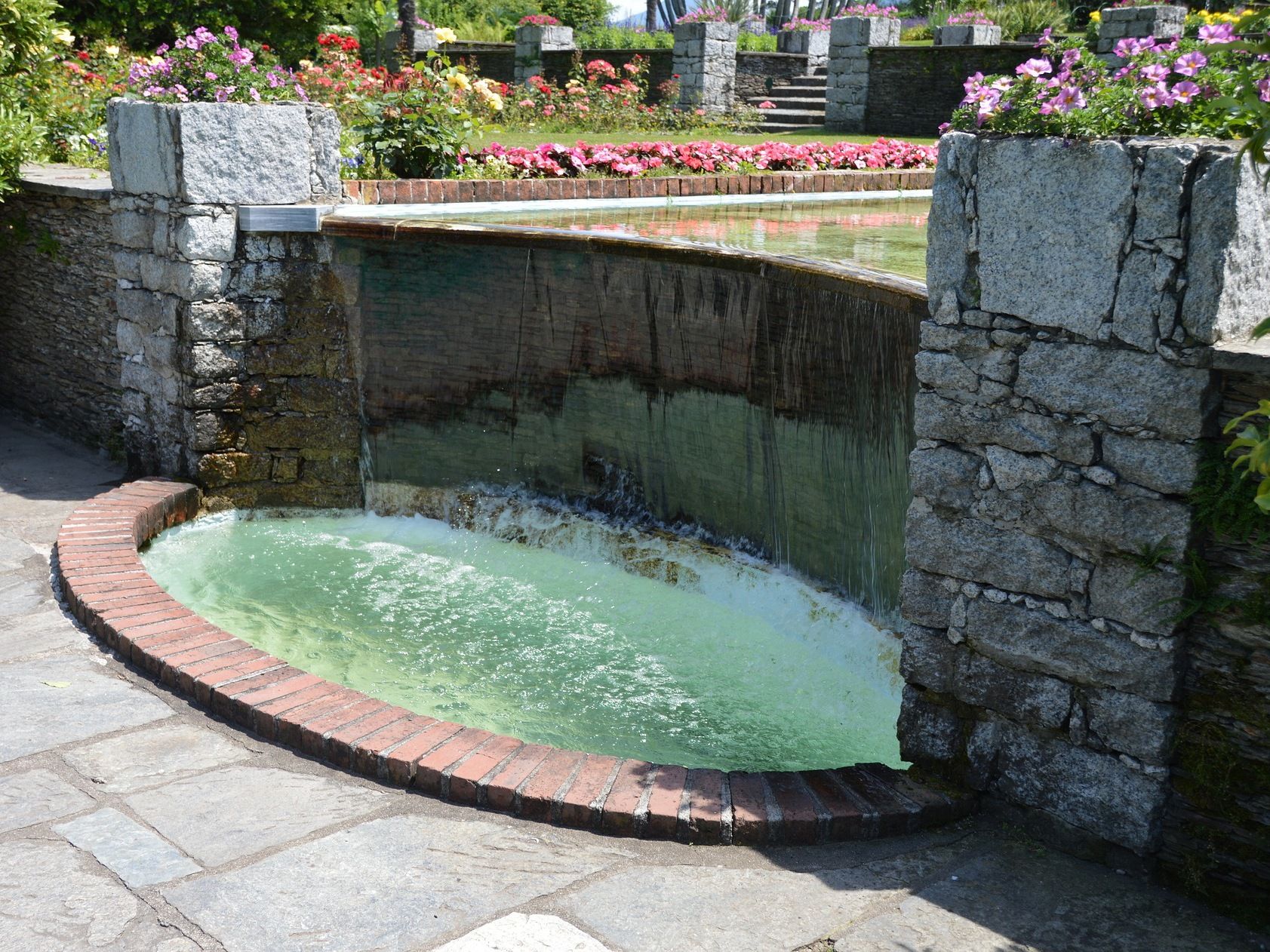 wasserfall in locarno umgeben von blumen und steinmauern, perfekter ort zum entspannen