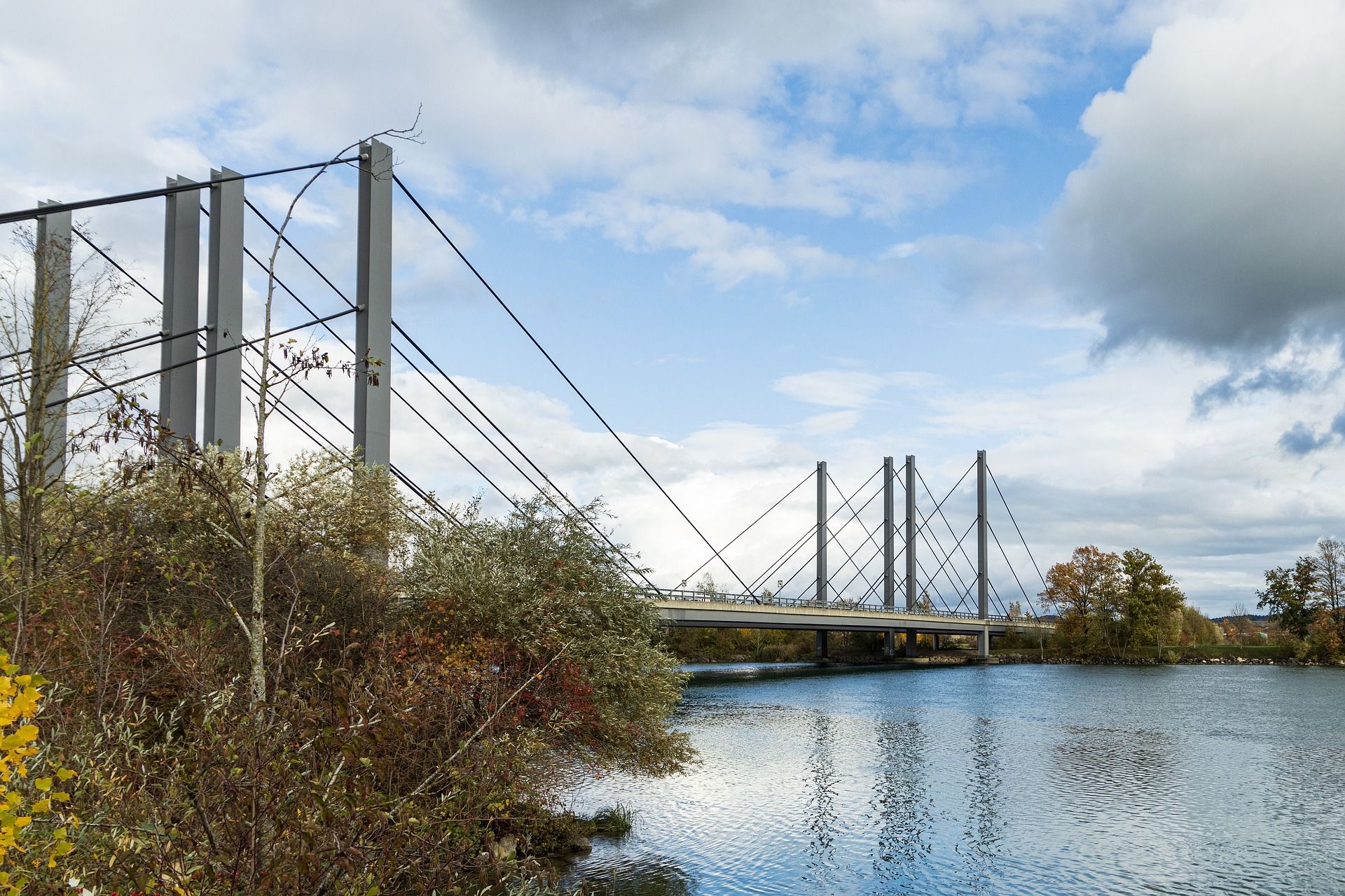 Ponte sul fiume Aare a Grenchen con riva verde e cielo nuvoloso.