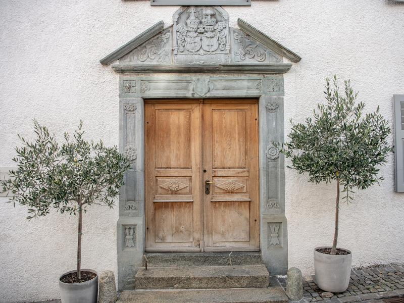 Tor in Ilanz: Historisches Tor umgeben von Olivenbäumen in der Altstadt von Ilanz