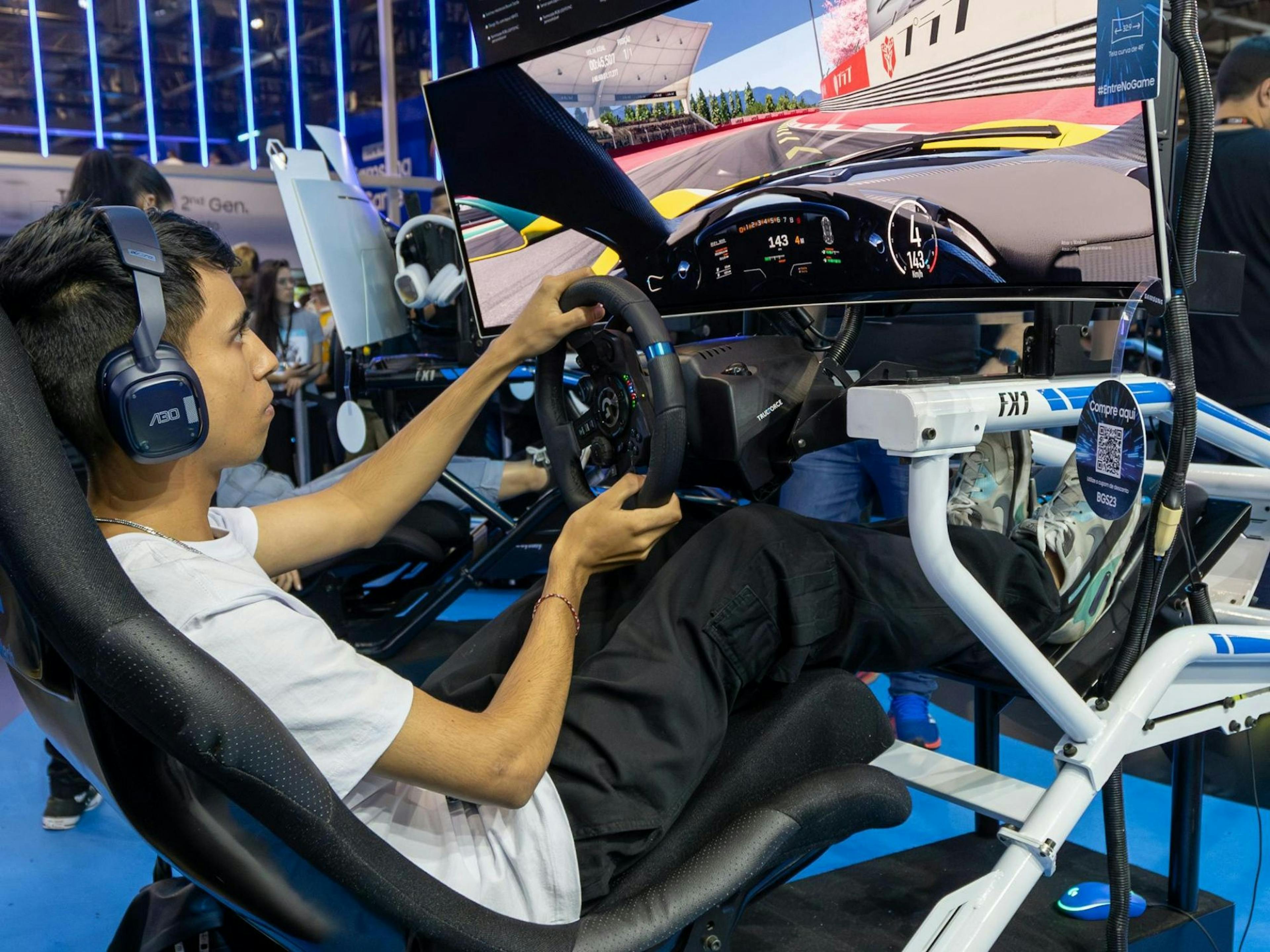 Simracing : Jeune personne joue sur un simulateur de course lors d'un événement avec un super setup gaming