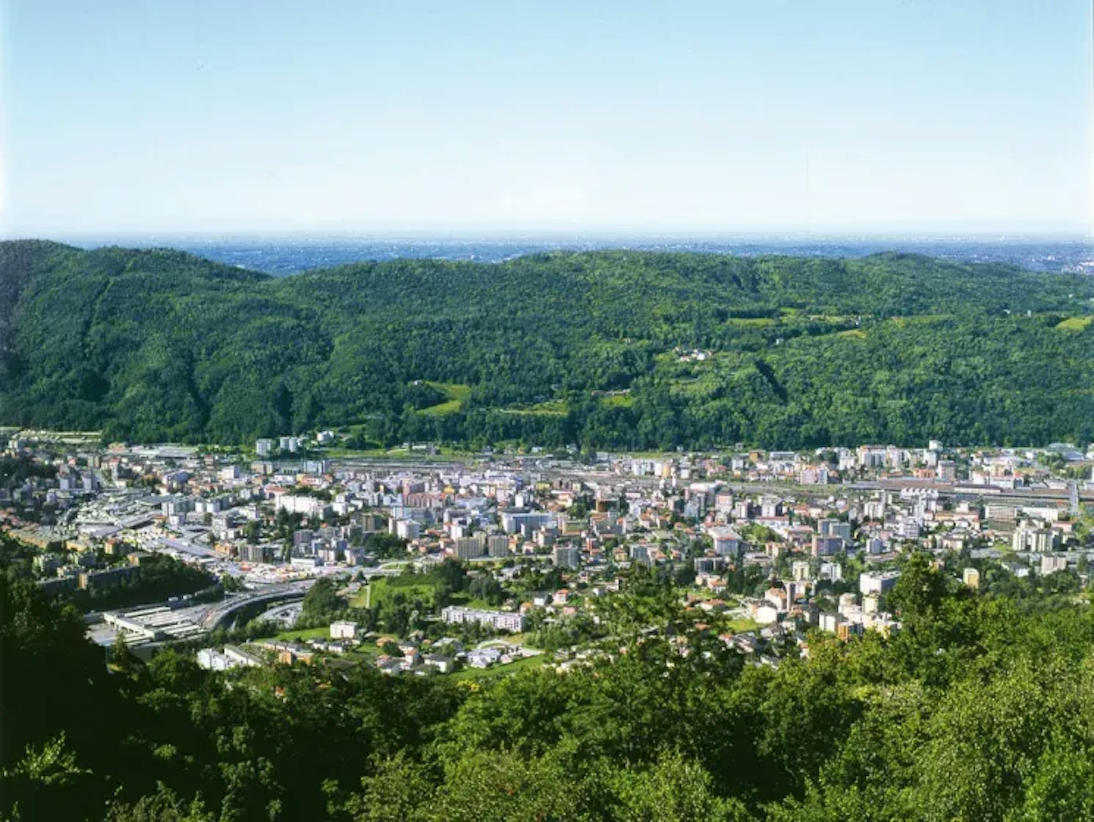 Chiasso Stadtansicht mit grünen Hügeln und vielen Gebäuden.