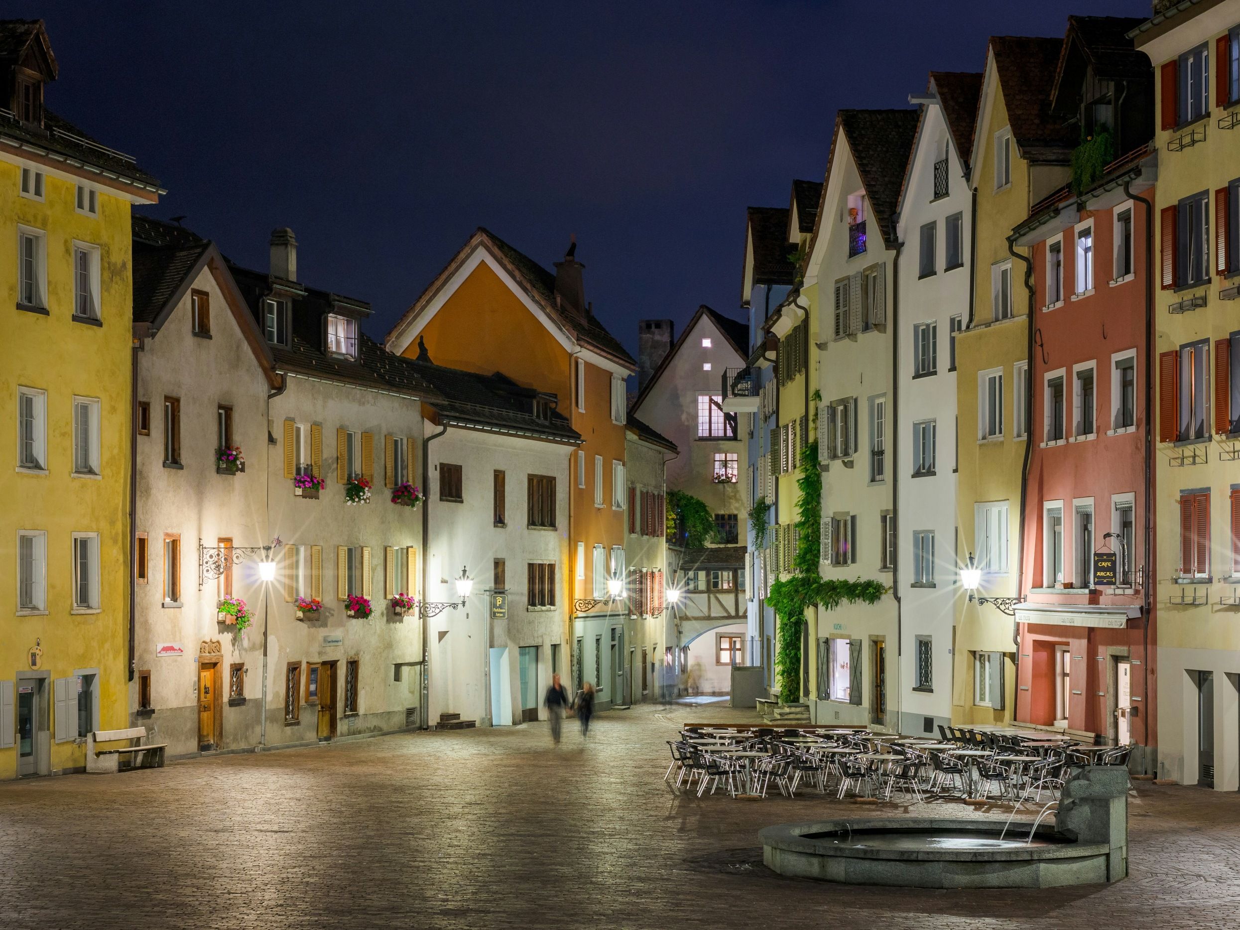 Stadsplats på natten med färgglada fasader, restauranger och mysig stämning