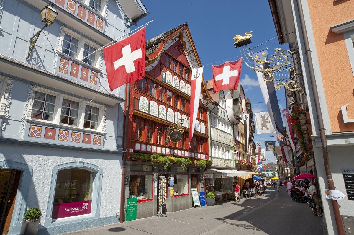 Appenzell village with typical houses and Swiss flags.