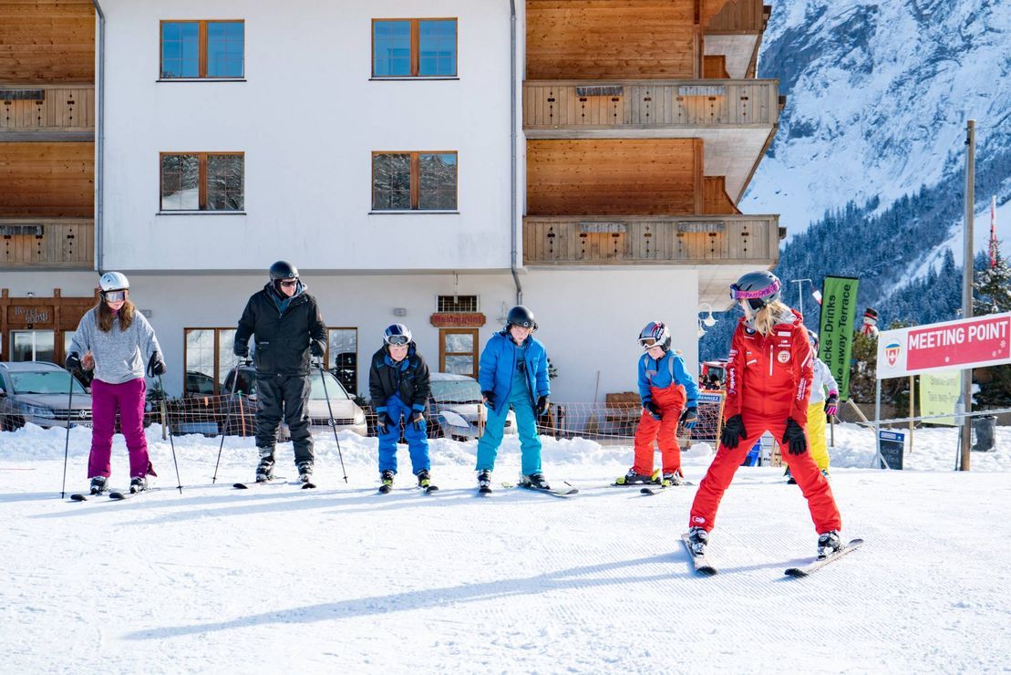 วันครอบครัวในกริลด์ลวัลด์กับการเล่นสกี มีคนหกคนอยู่บนสกี หิมะ ทิวทัศน์ภูเขา.