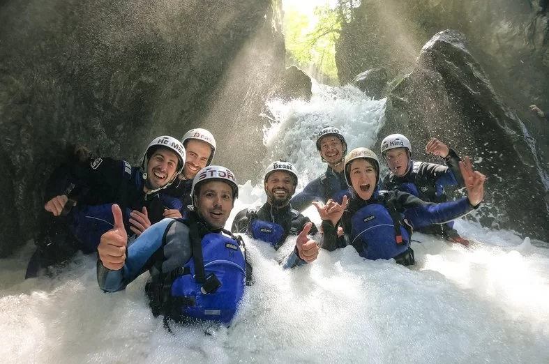 Canyoning Interlaken com um grupo em equipamento azul, cercado por cascatas e rochas.