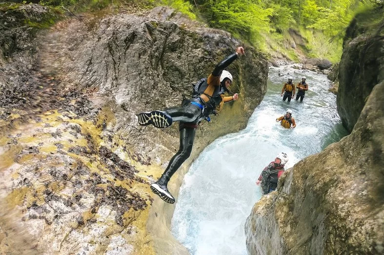 Canyoning Interlaken with a jump into the water, group in wetsuits