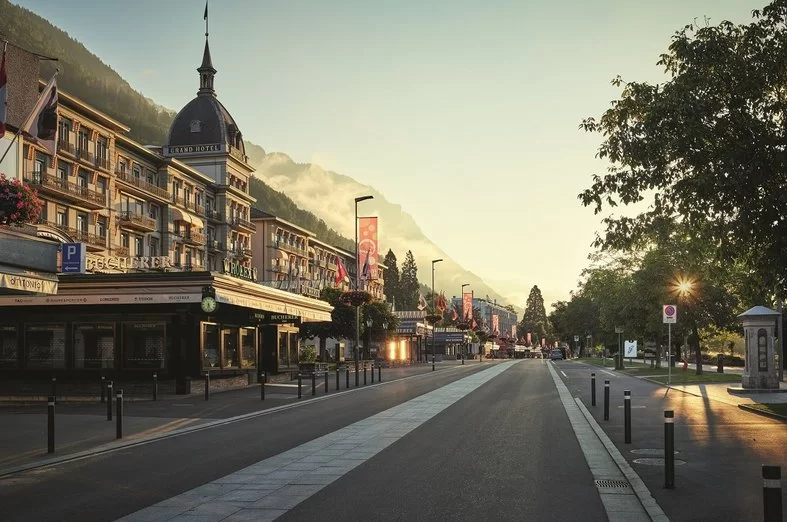 Victoria Jungfrau Hotel in Interlaken am Hohweg bei Sonnenaufgang, ruhige Straße mit bunten Fahnen