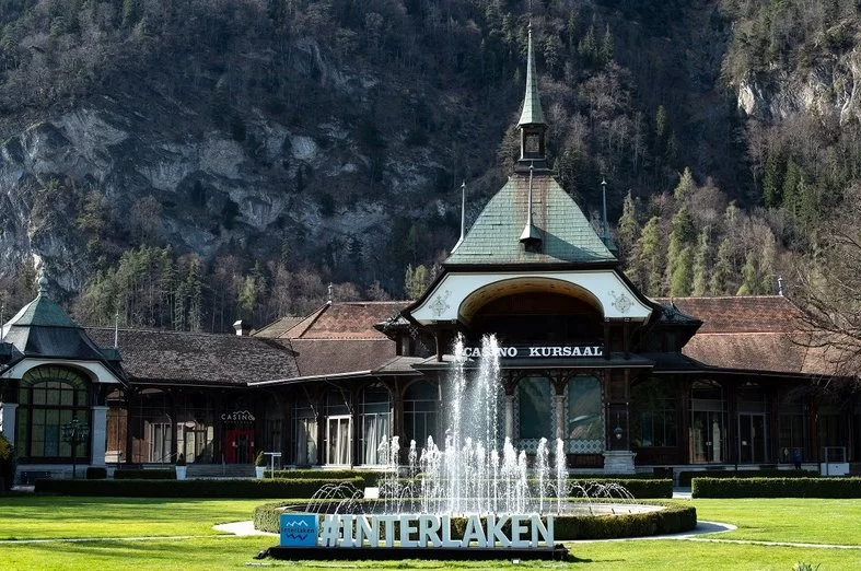 Casino in Interlaken mit Brunnen und Berg im Hintergrund.