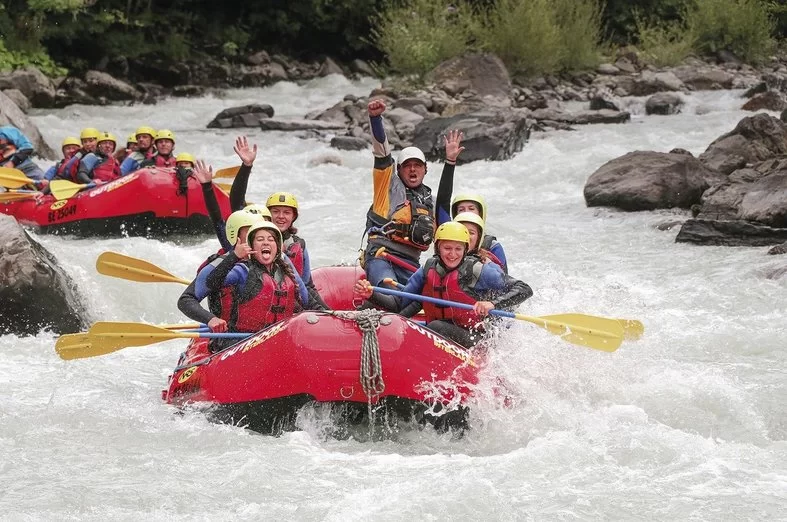 Rafting Abenteuer auf der Lutschine mit Teilnehmern in roten Booten.