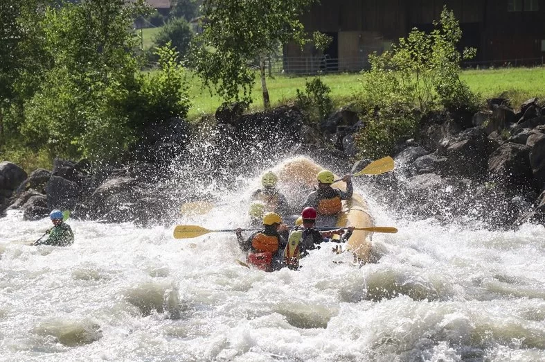 Rafting Abenteuer auf der Lutschine mit starkem Wasserfluss und grüner Umgebung.