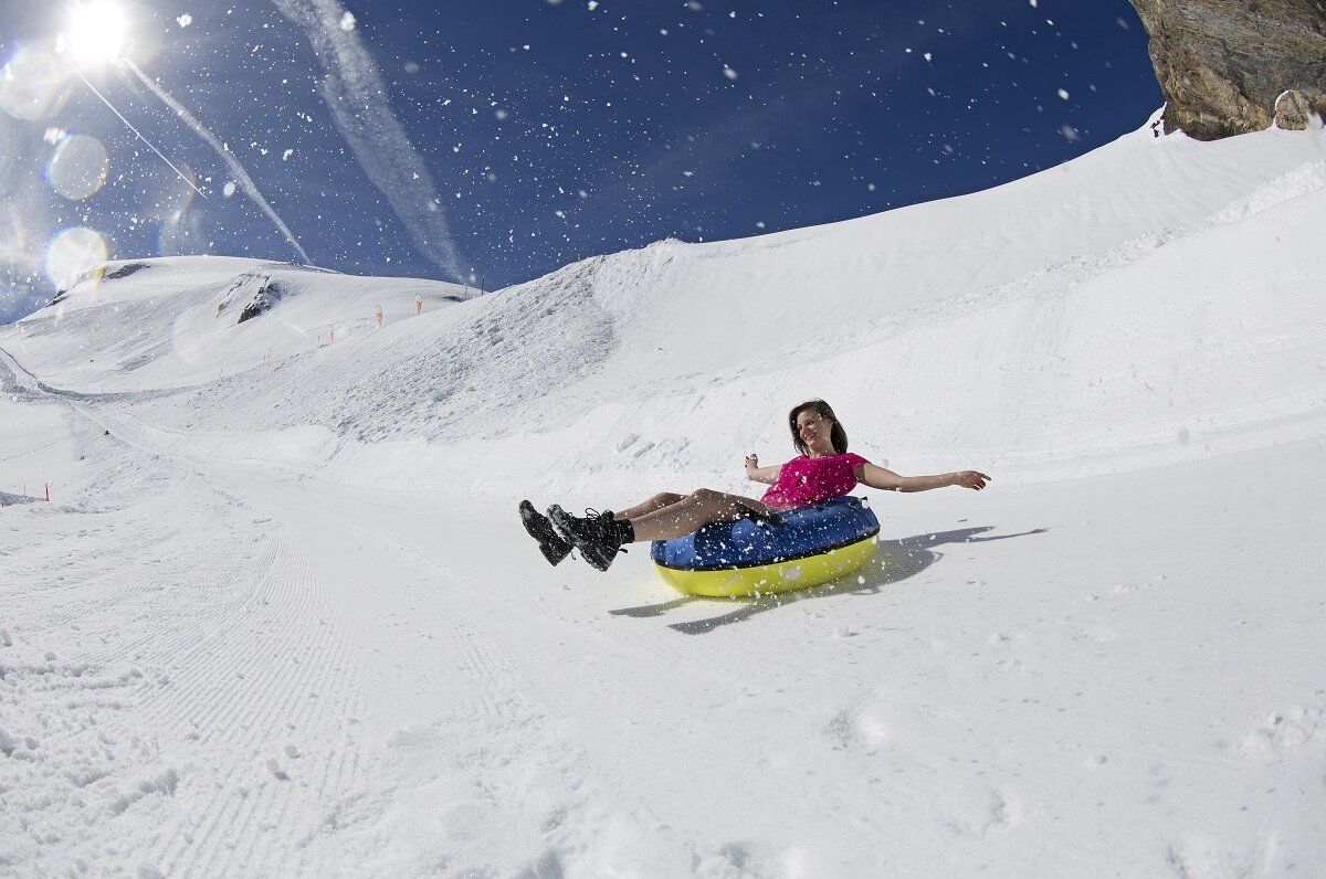 Titlis Tagesausflug: Frau rutscht auf Tube im Schnee, klare Bedingungen