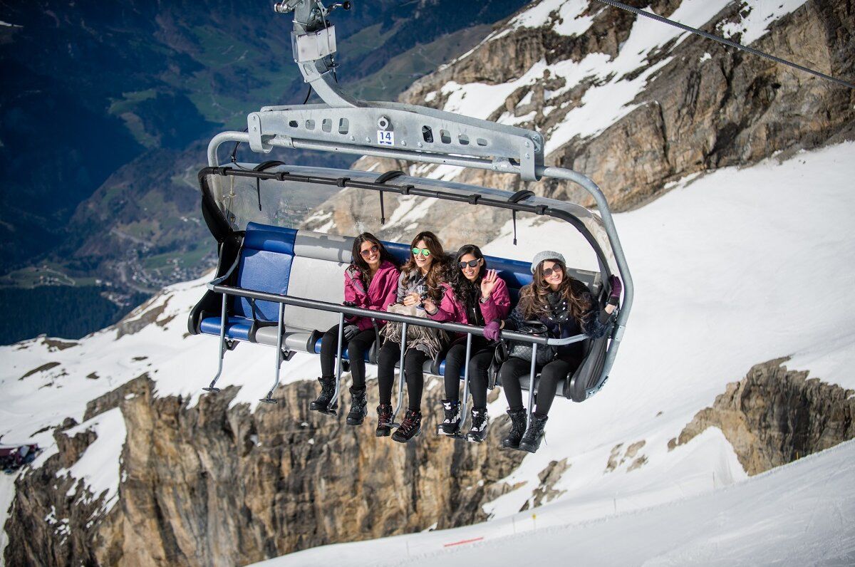 Titlis Eis Flyer mit Personen auf der Sesselbahn, Schnee und Berge sichtbar.