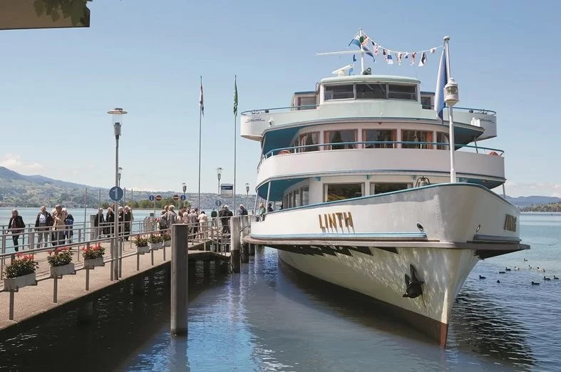 Zurich: Pelabuhan kapal di Bürkliplatz dengan pemandangan danau Zürich dan sebuah bot. Cuaca cerah.