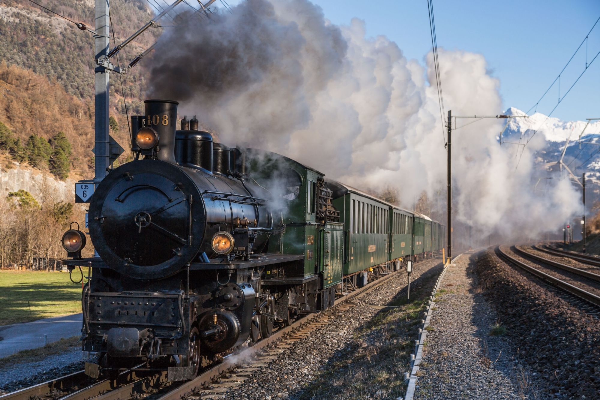 Steam trip Surselva with steam locomotive runs along the tracks