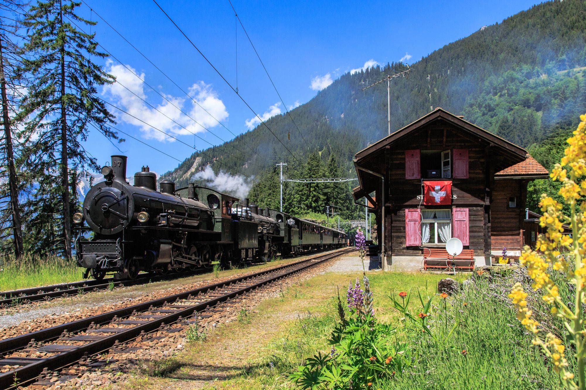 Engadin round trip with steam train at a train station surrounded by mountains