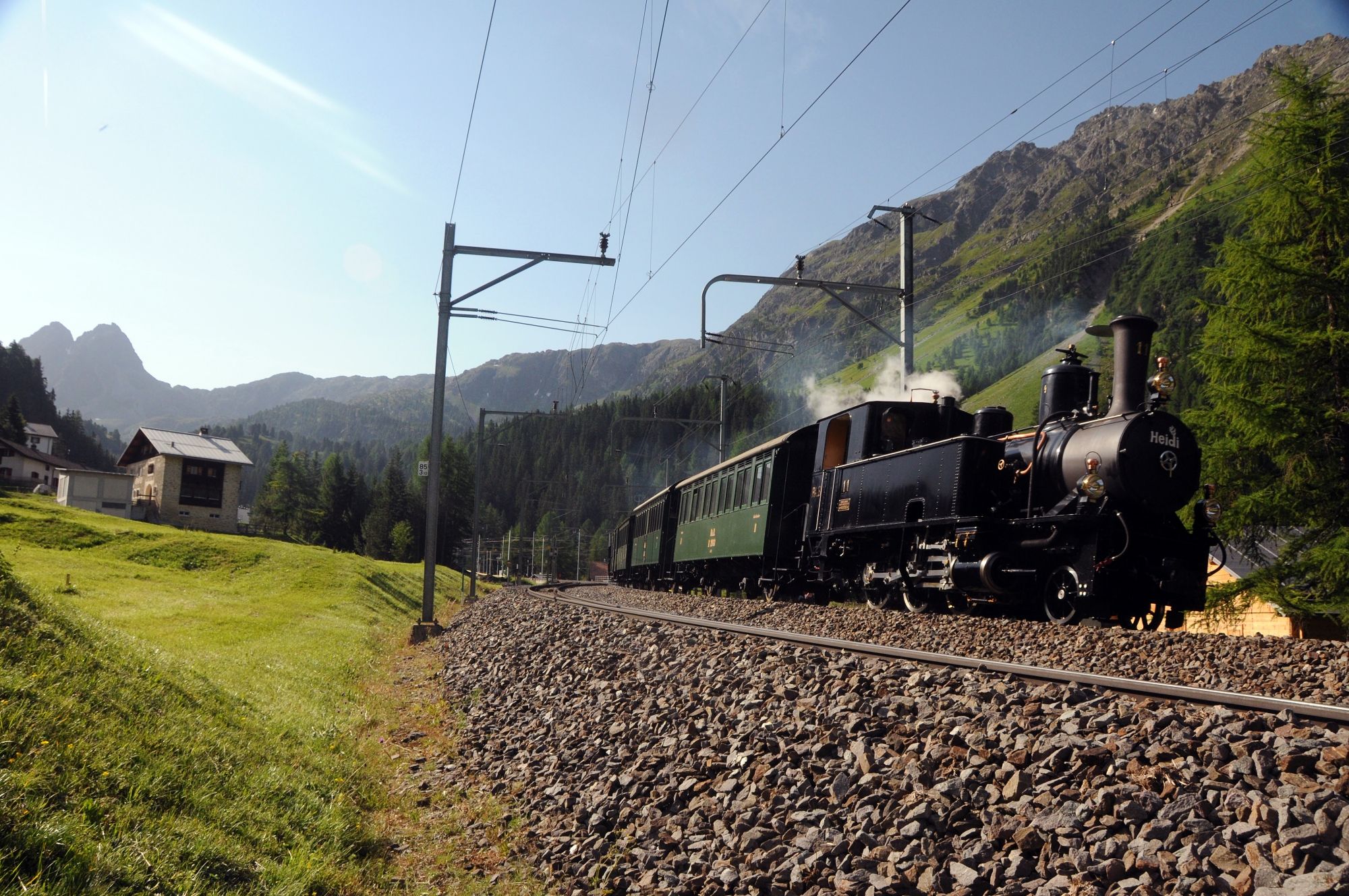 Engadin steam trip with steam locomotive on a picturesque route in the mountains.