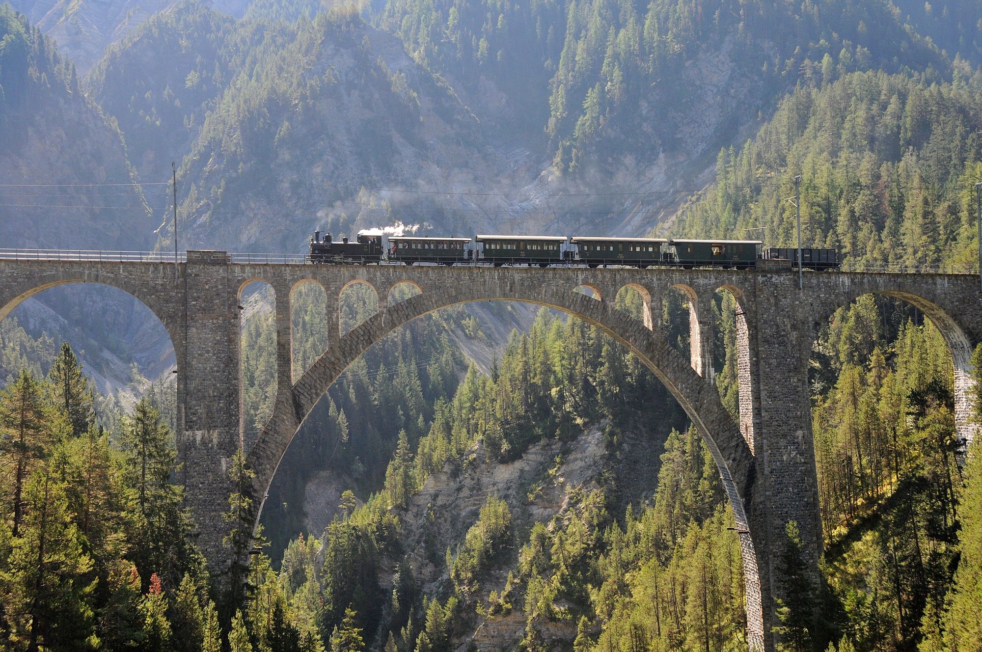 Steam ride Surselva on a historic bridge in nature.