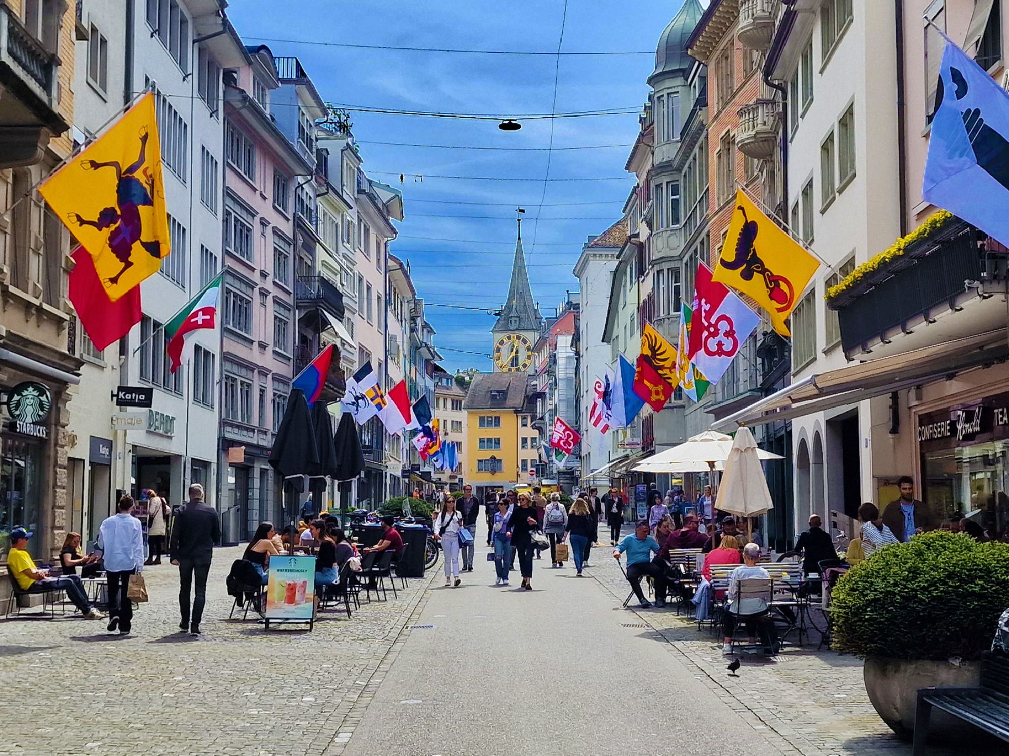 Zürich Innenstadt: belebte Straße mit Cafés und bunten Fahnen, ideal für einen Tagesausflug.