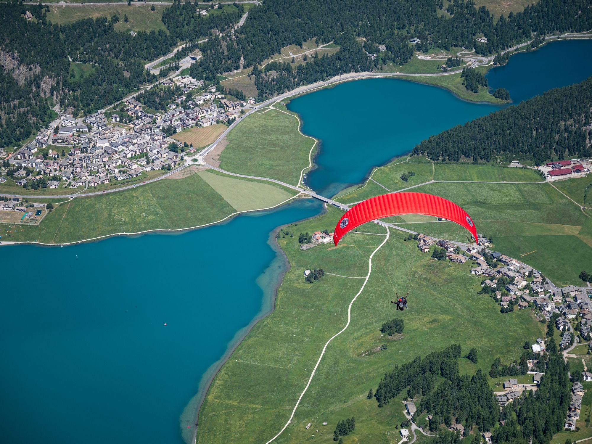 Gleitschirmfliegen: Tandemflug über St. Moritz und das Engadin mit Blick auf glitzernde Seen.