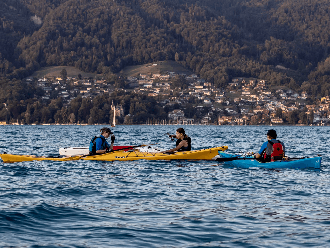 بحيرة ثون: عدة زوارق كاياك على الماء، أنشطة في الطبيعة على البحيرة، أشخاص يمارسون رياضة الكاياك.