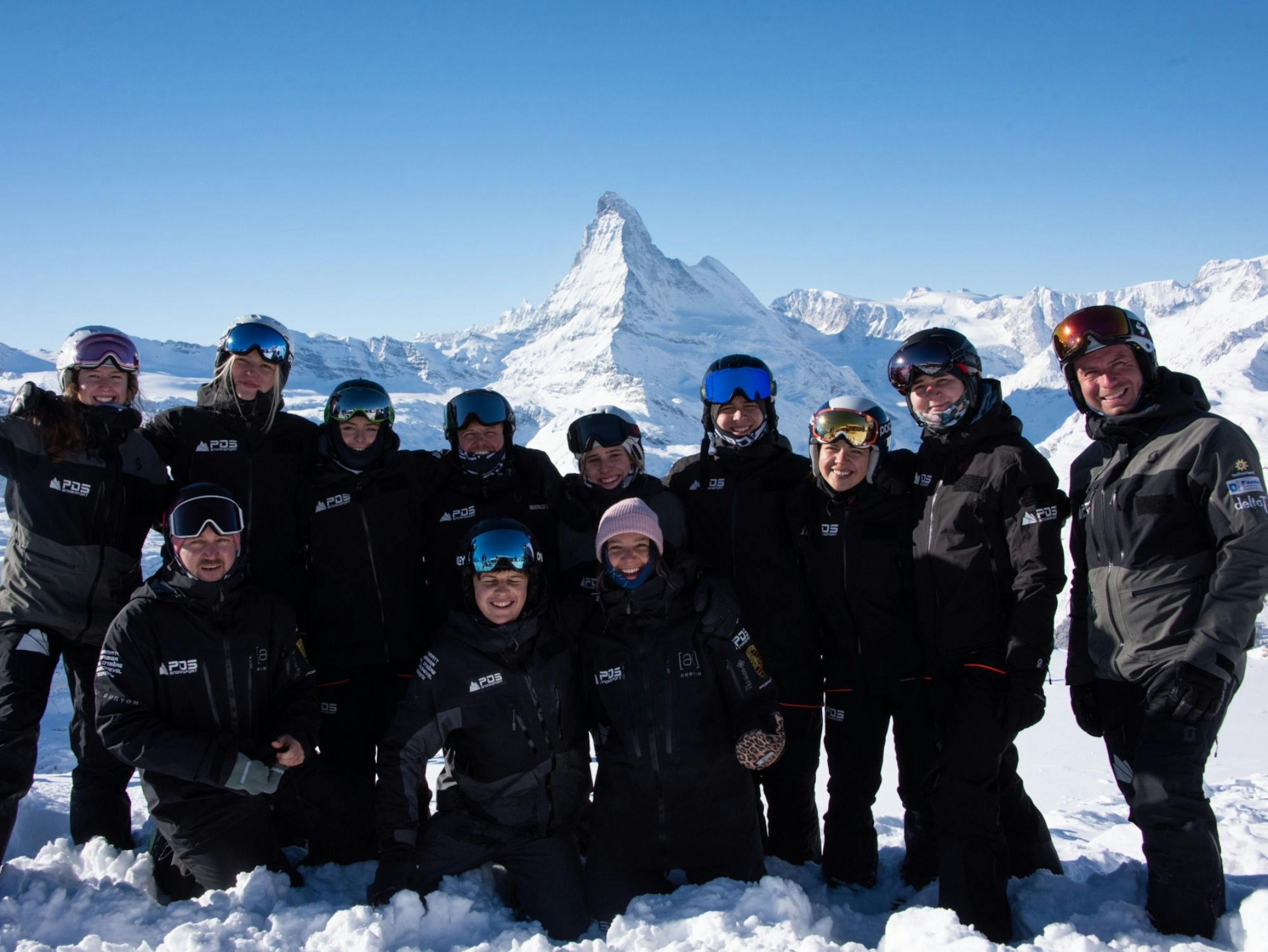 Escola de Esqui: Equipa PDS em Zermatt diante do Matterhorn no inverno, condições ideais para aulas de esqui.