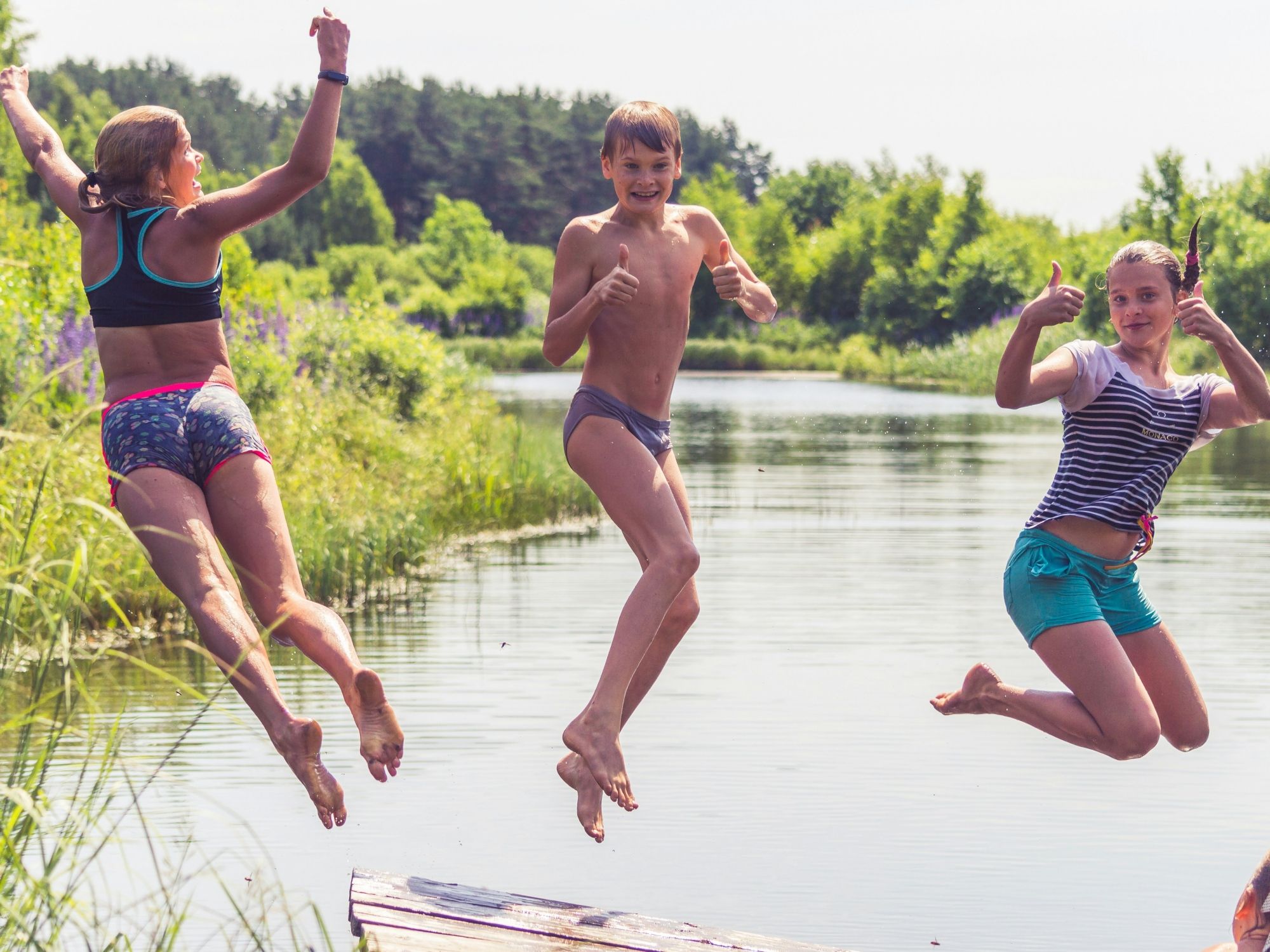 Baden: Barn leker glatt i den klara sjön i naturen under sommardagen.