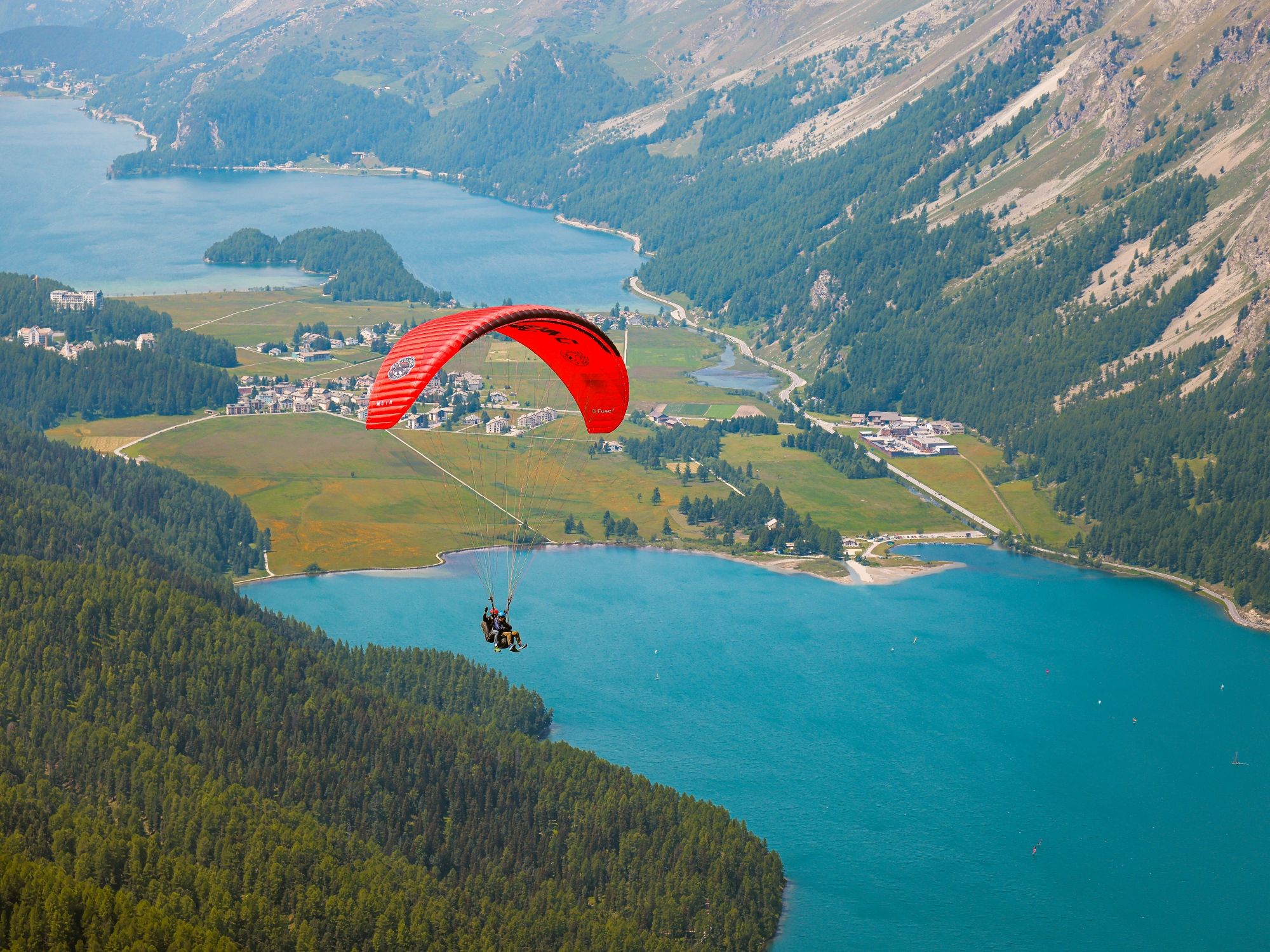 Paragliding: Tandem flight in the Engadin over picturesque lakes and mountains, perfect for adventure seekers.