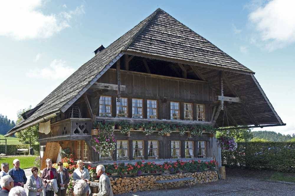 Dom w tradycyjnym szwajcarskim stylu, kwiaty i stos drewna