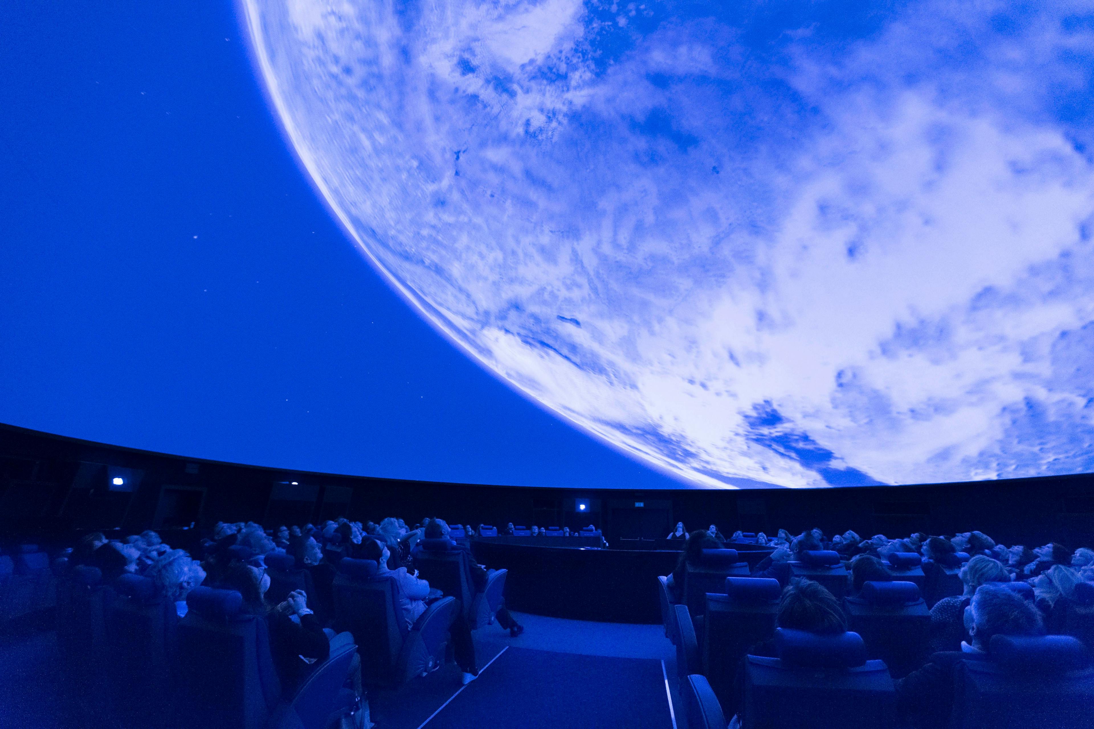 Planetarium Live im Verkehrshaus mit Besuchern unter einem blauen Himmelsprojektion